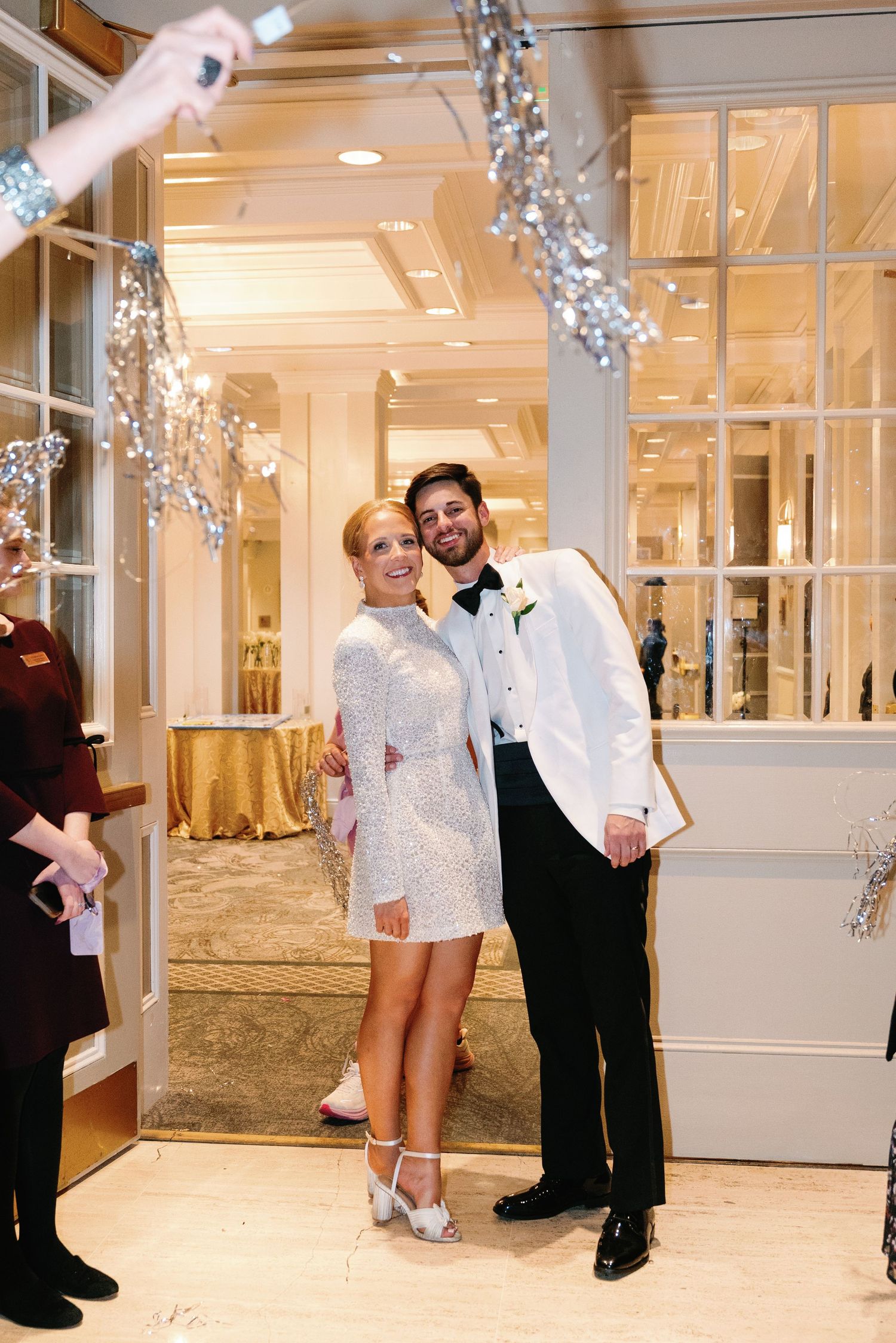 Wedding couple poses playfully in a bright indoor venue decorated with twinkling lights.