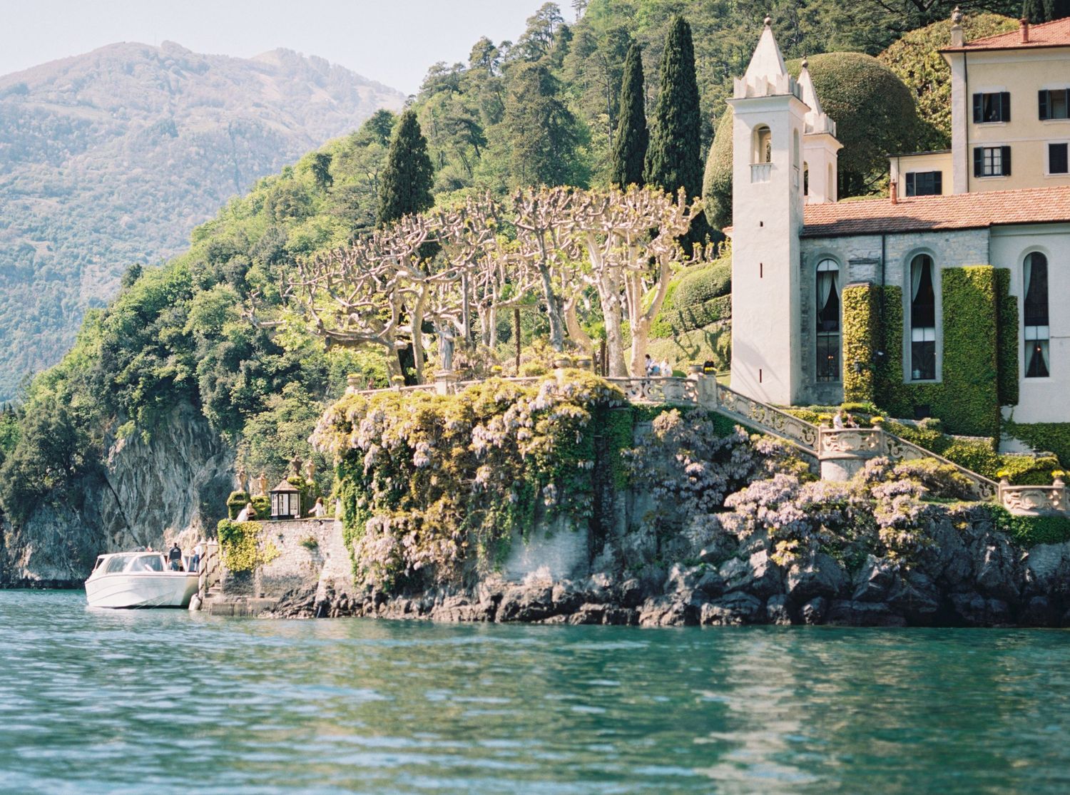 Mediterranean coastal scene with luxury villas nestled among cliffs and cypress trees.