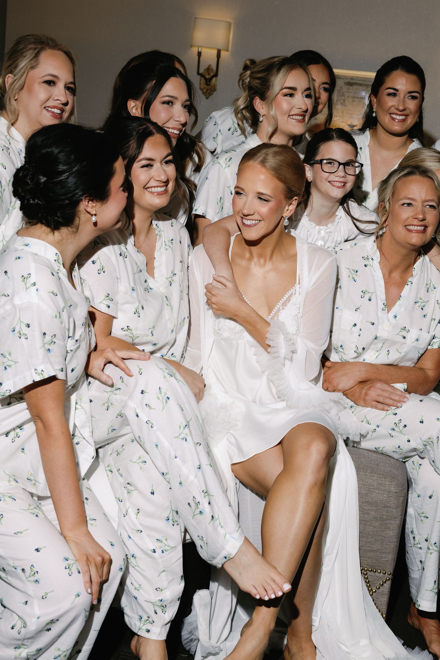Group wearing matching floral robes pose together during wedding preparation.