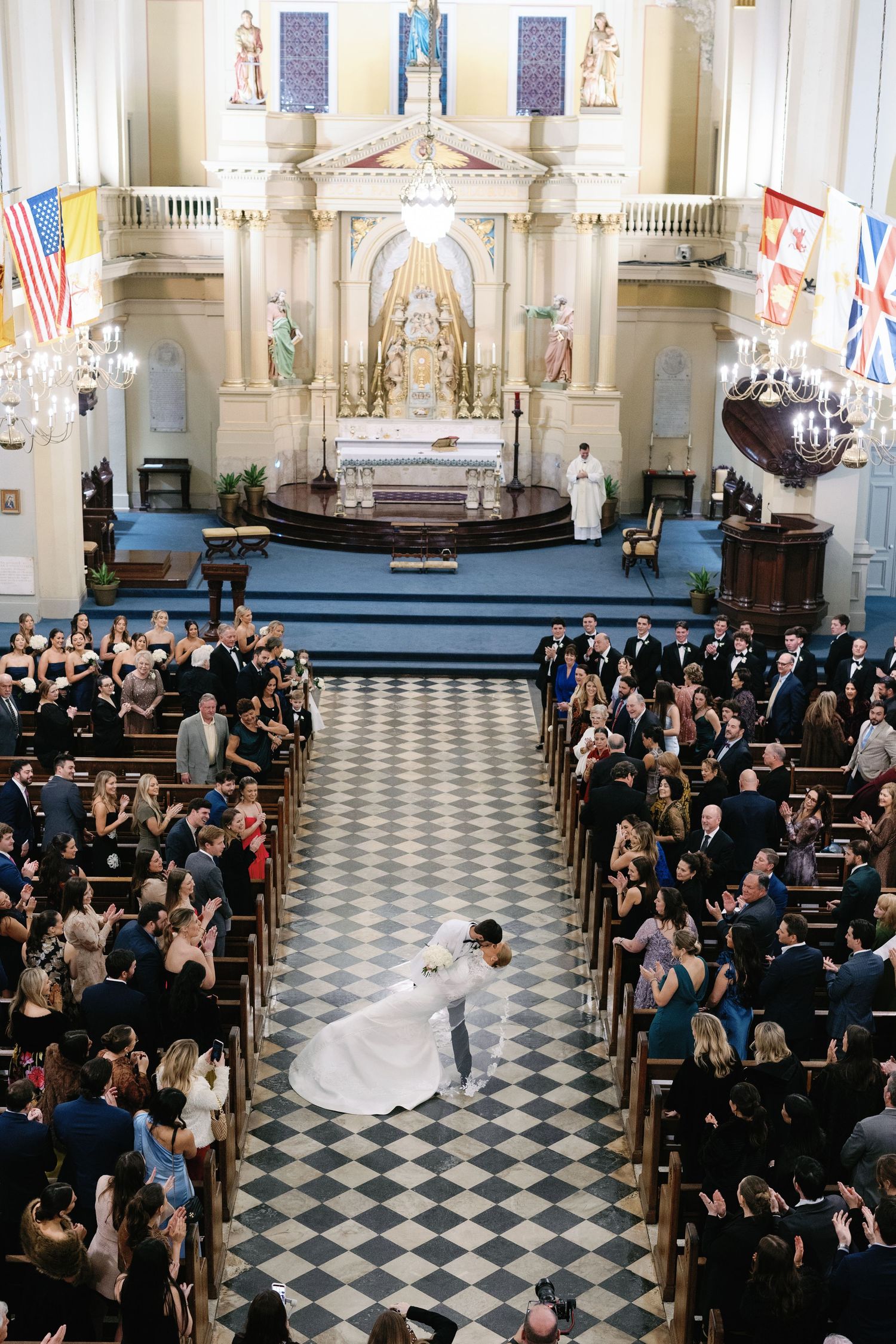 Overhead view of wedding ceremony in historic church with checkered floor and full pews.