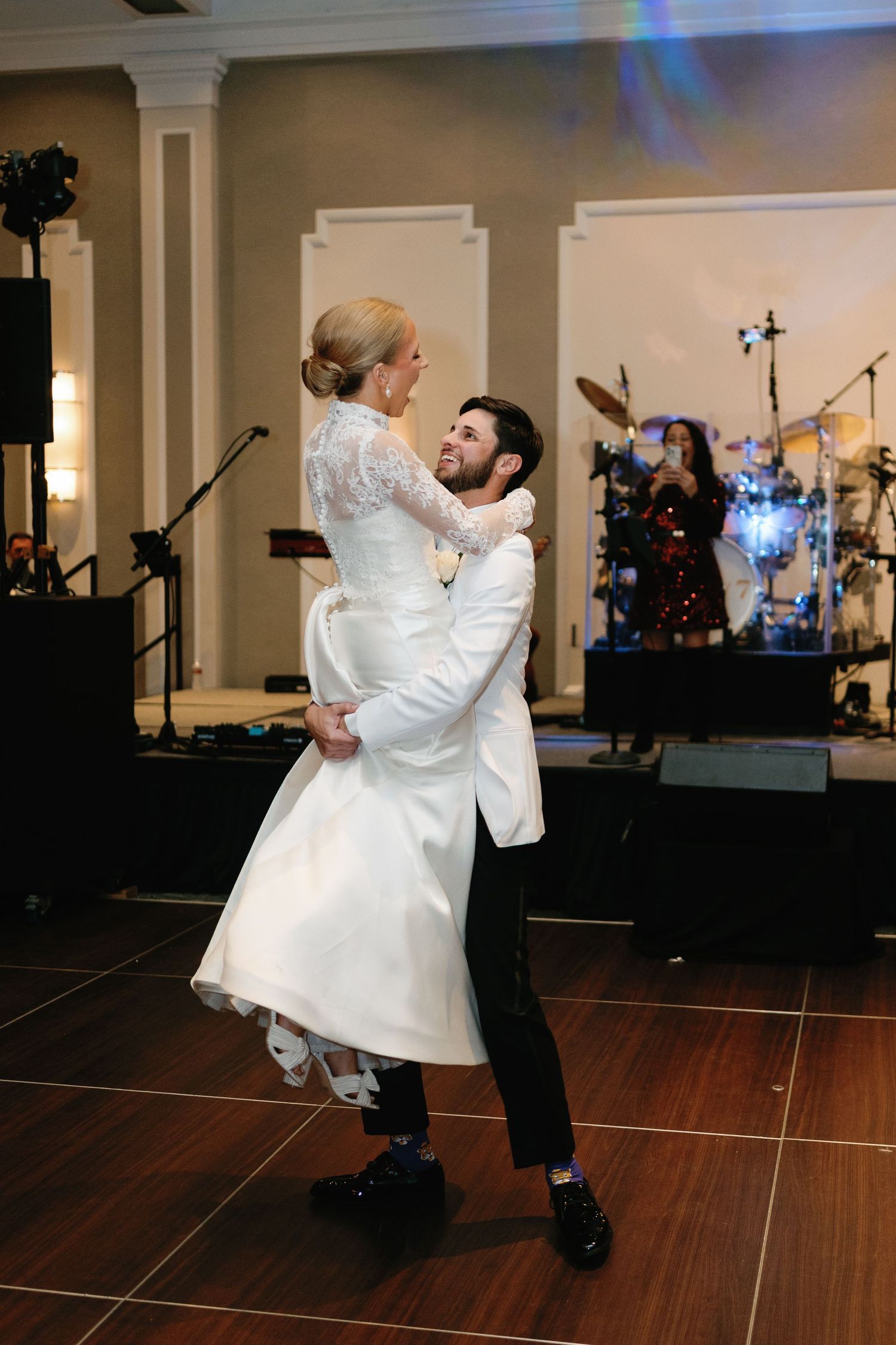 Wedding couple performs energetic dance moves on a dark wooden dance floor.