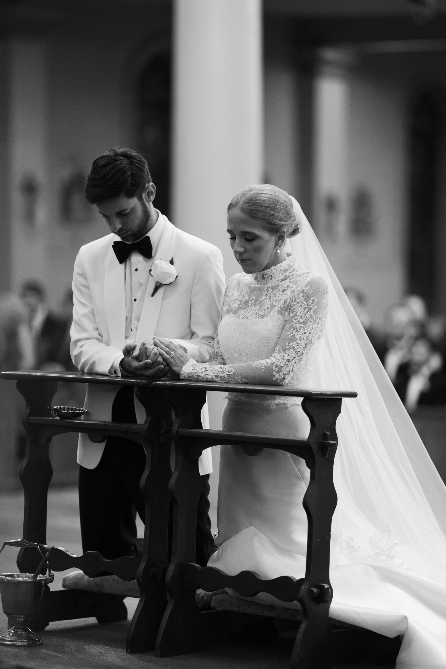 Black and white photo of a couple praying together during their wedding ceremony.