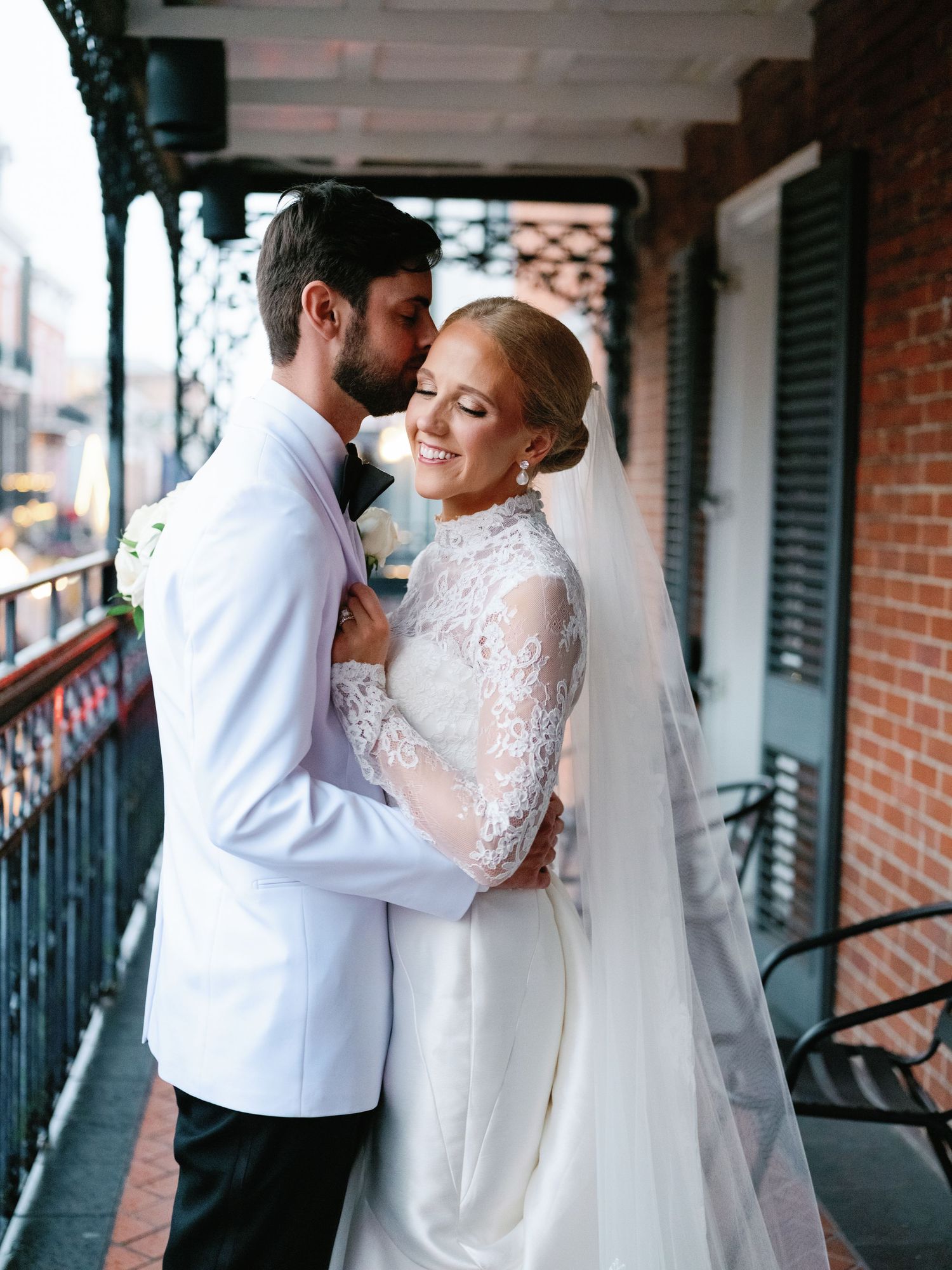 A romantic dance sequence on a historic balcony with white columns and brick walls.