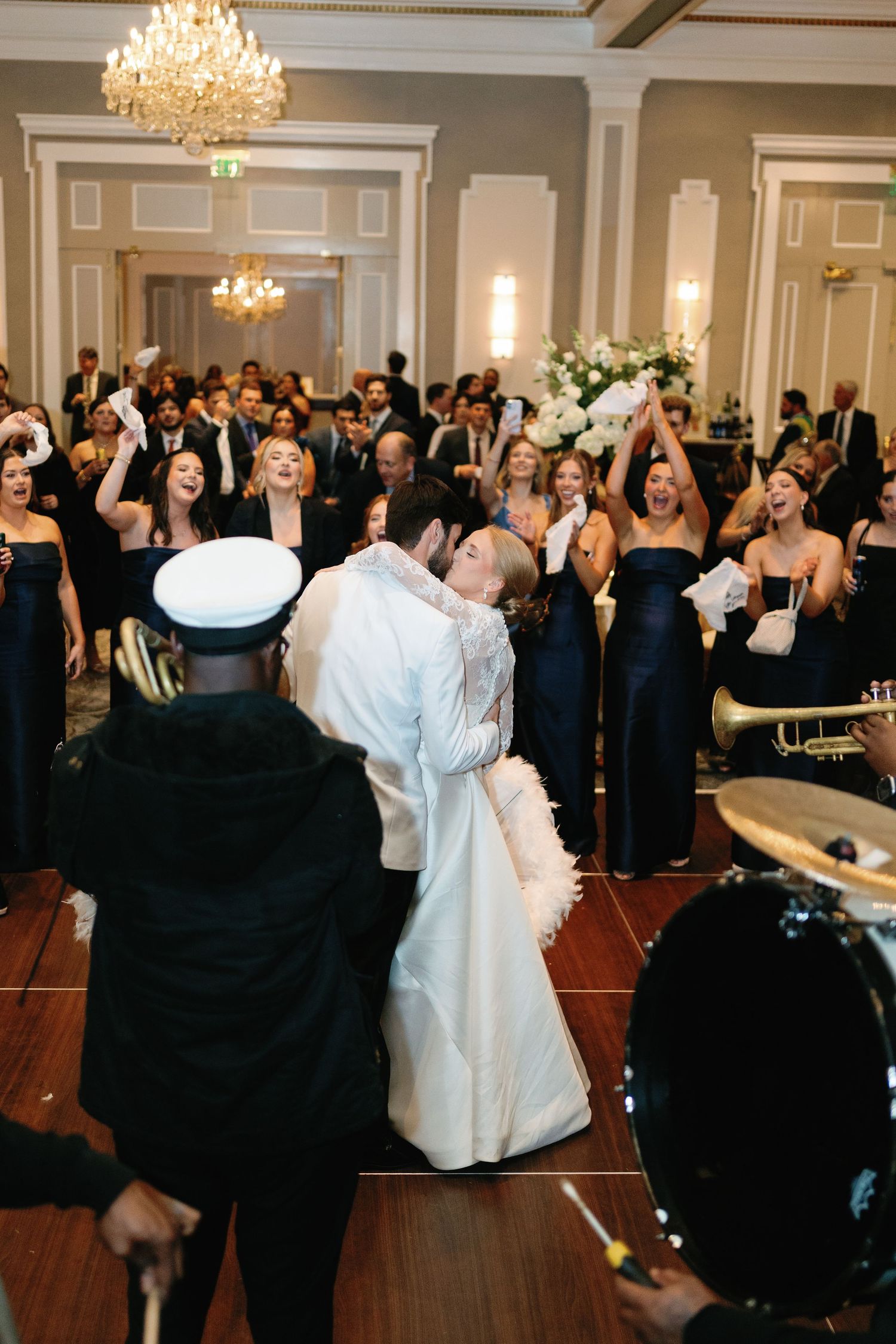 Wedding reception celebration with guests dancing under crystal chandeliers.