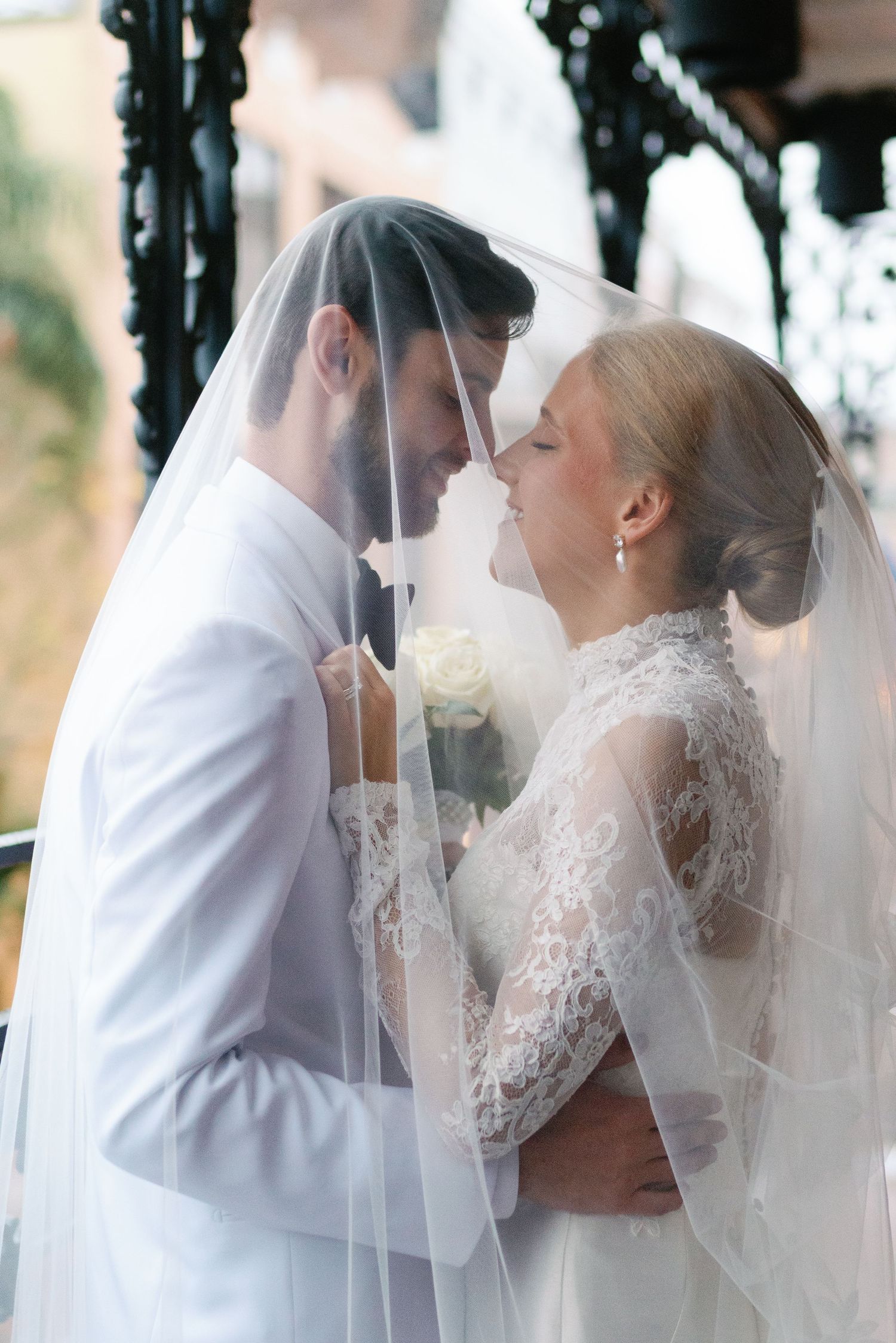 Romantic wedding moments captured through a delicate veil in natural lighting.