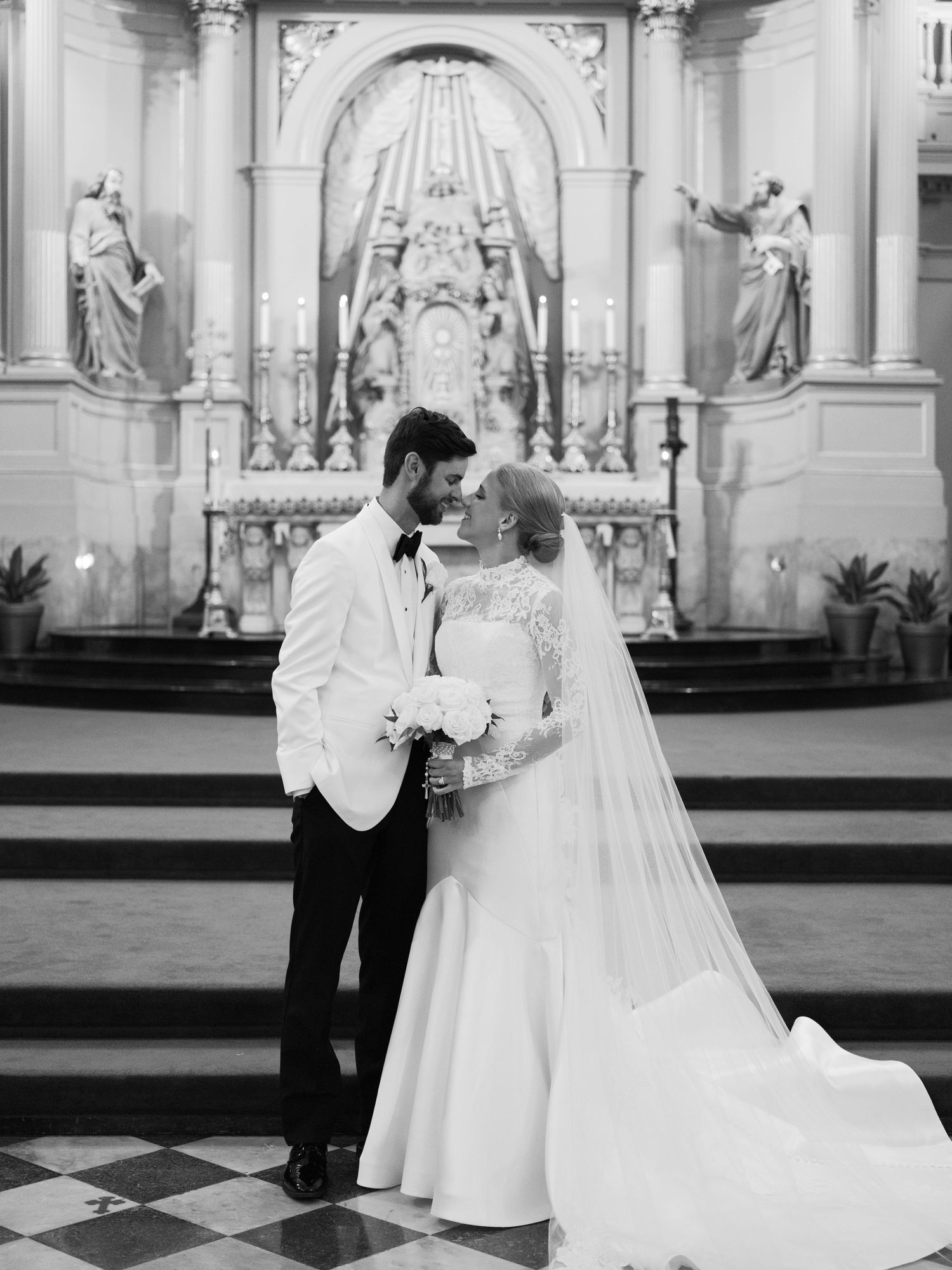 Wedding ceremony taking place in an ornate church with classical architecture and religious artwork.