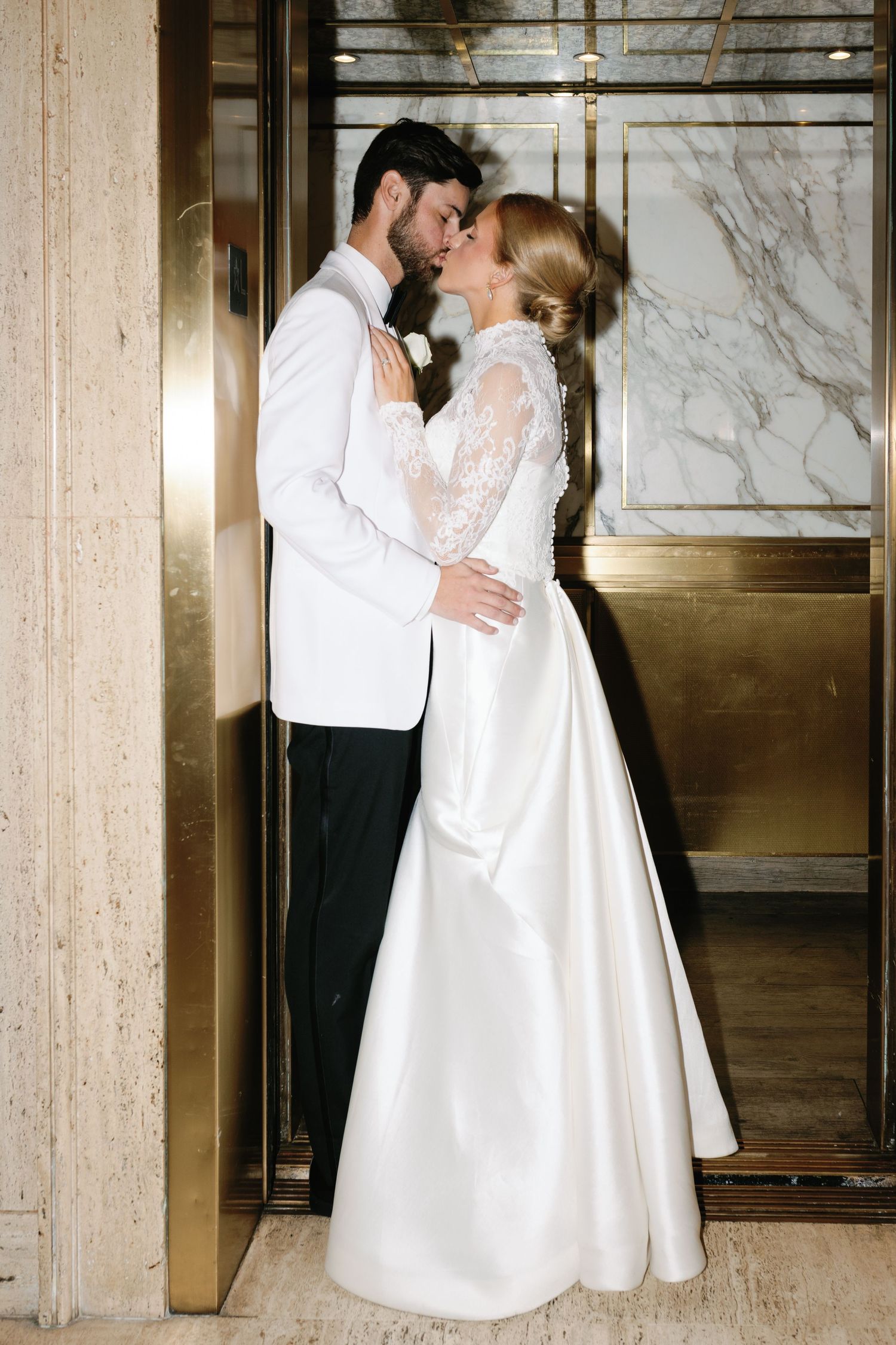 A romantic first dance moment captured in an elegant marble-walled venue with warm lighting.