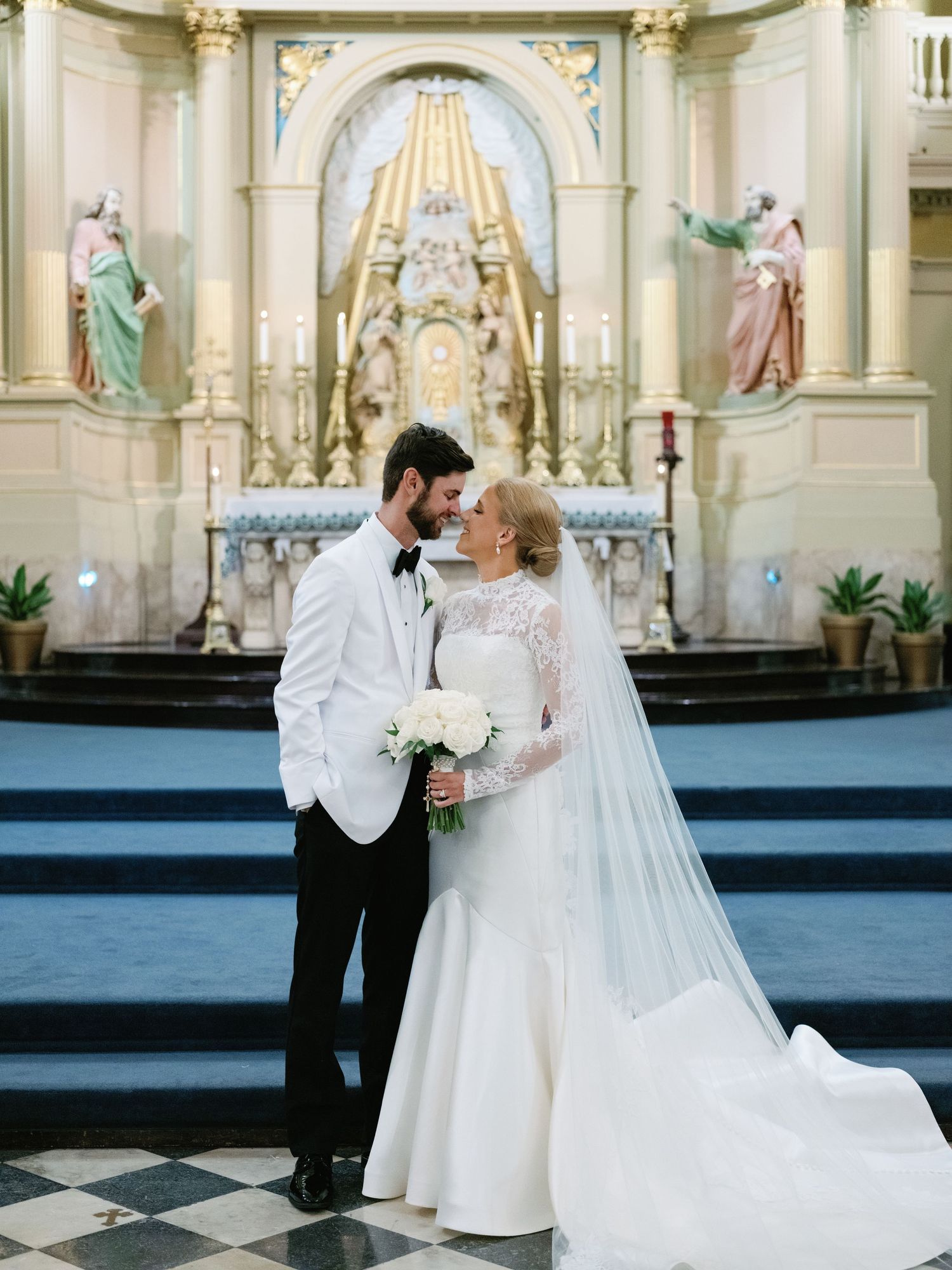 Elegant wedding couple sharing tender moment in ornate church setting.