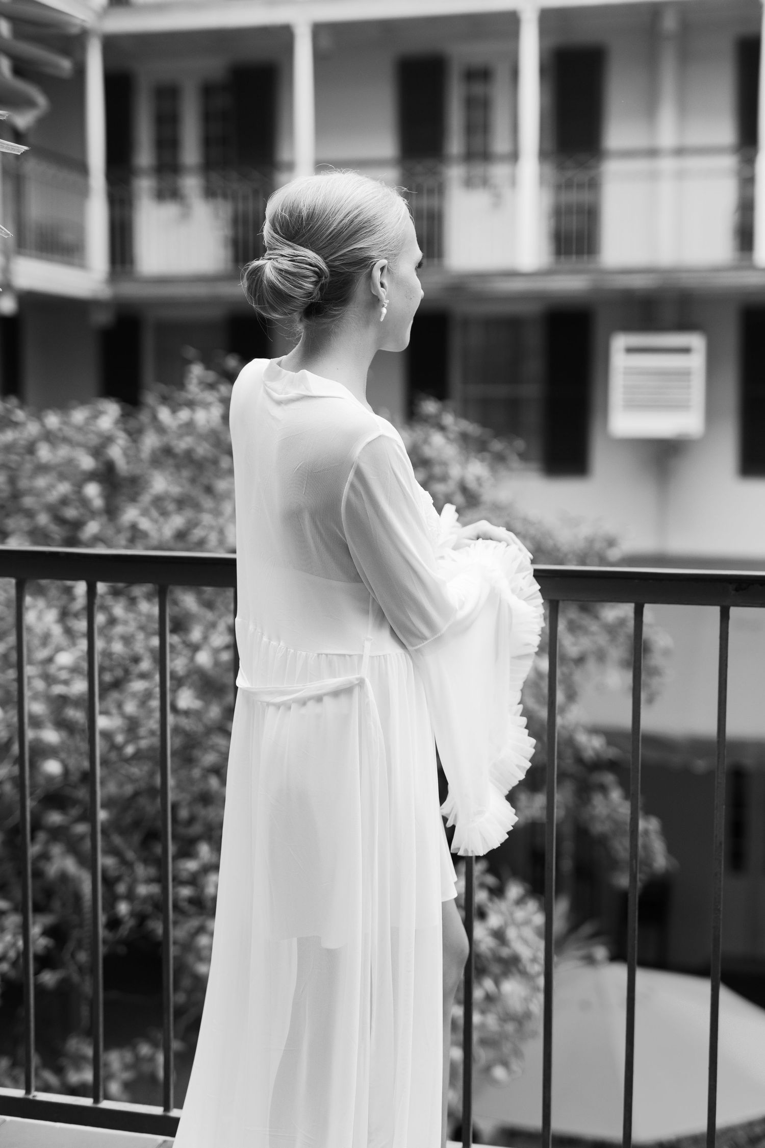 Silhouettes in white dresses standing on a balcony in black and white photography.