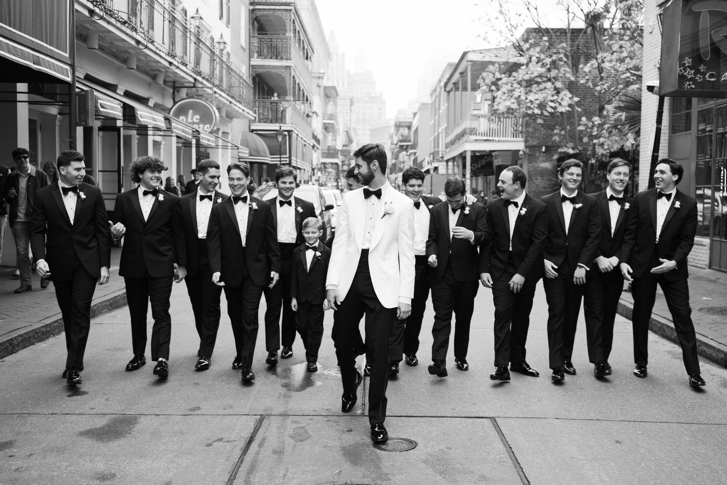 Black and white photo of groomsmen lined up on urban sidewalk.