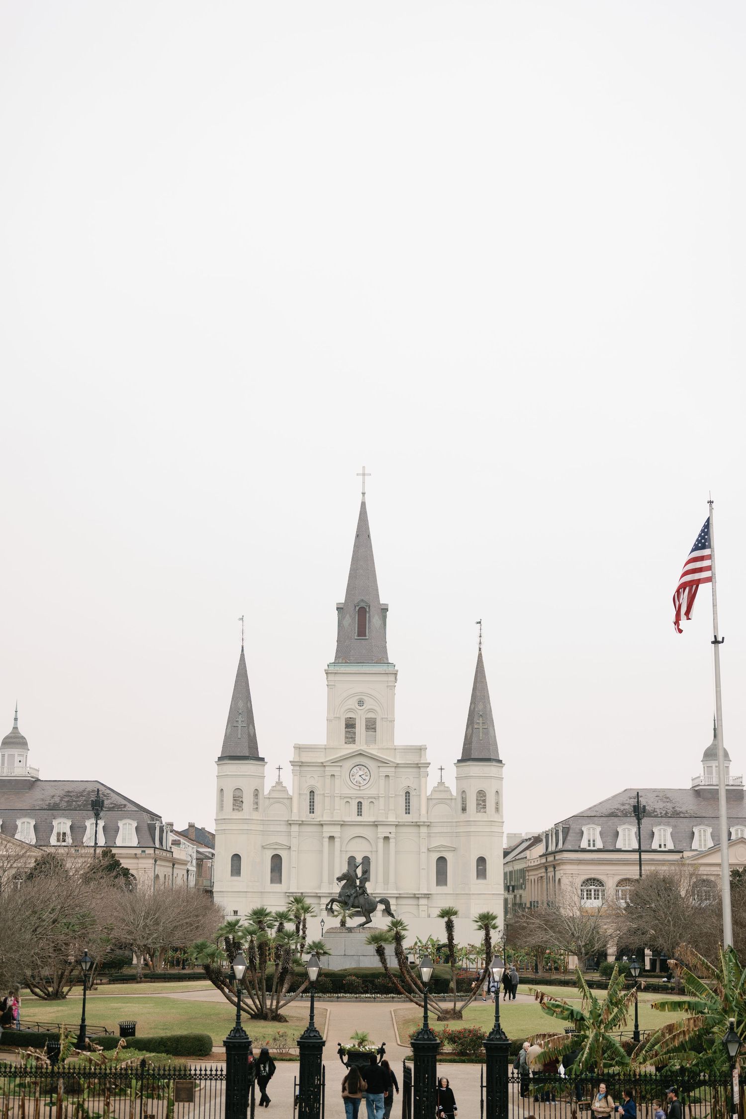 St. Louis Cathedral in New Orleans with American flag and Jackson Square statue in foreground.