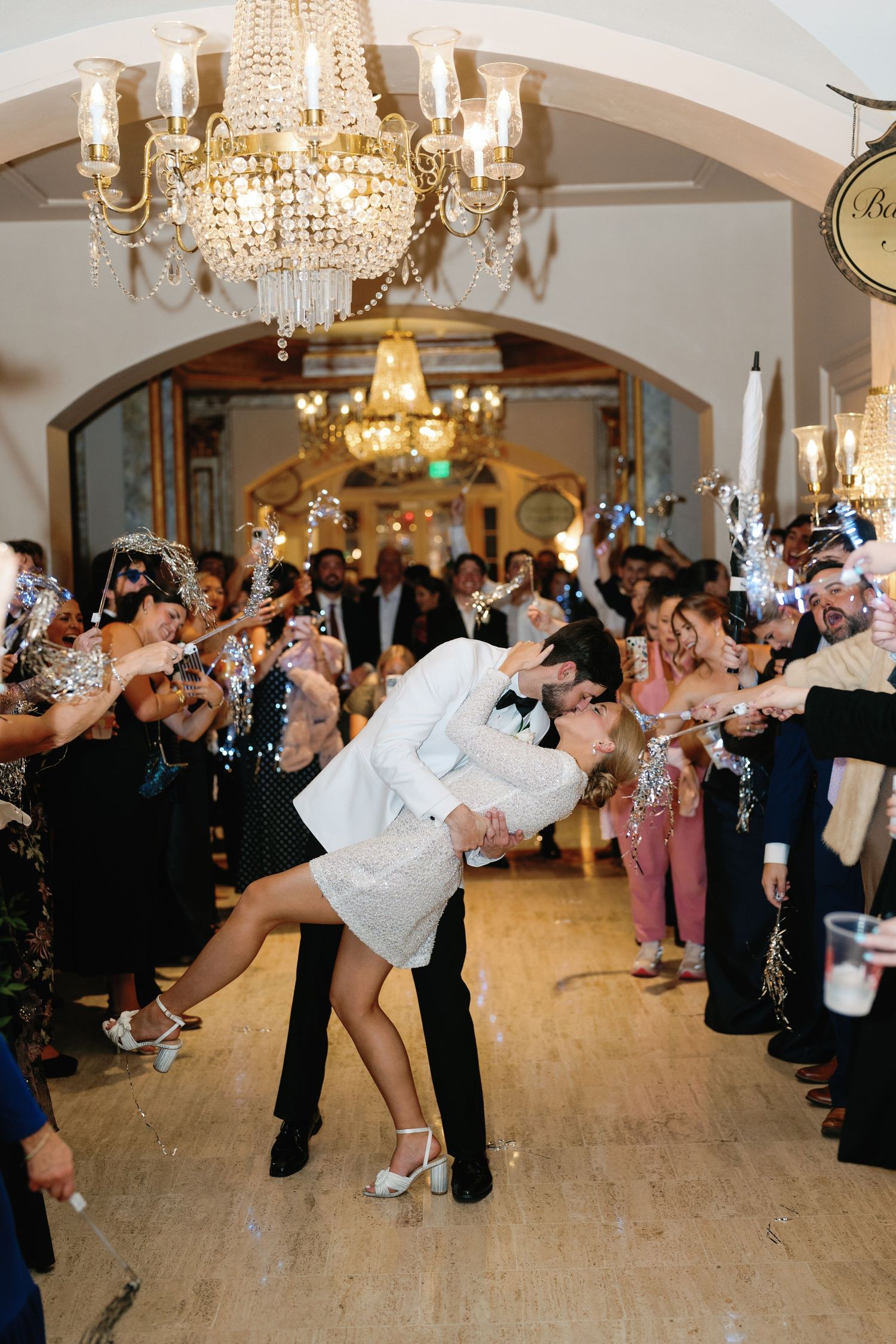 Wedding reception features multiple couples performing synchronized dance moves under crystal chandeliers.