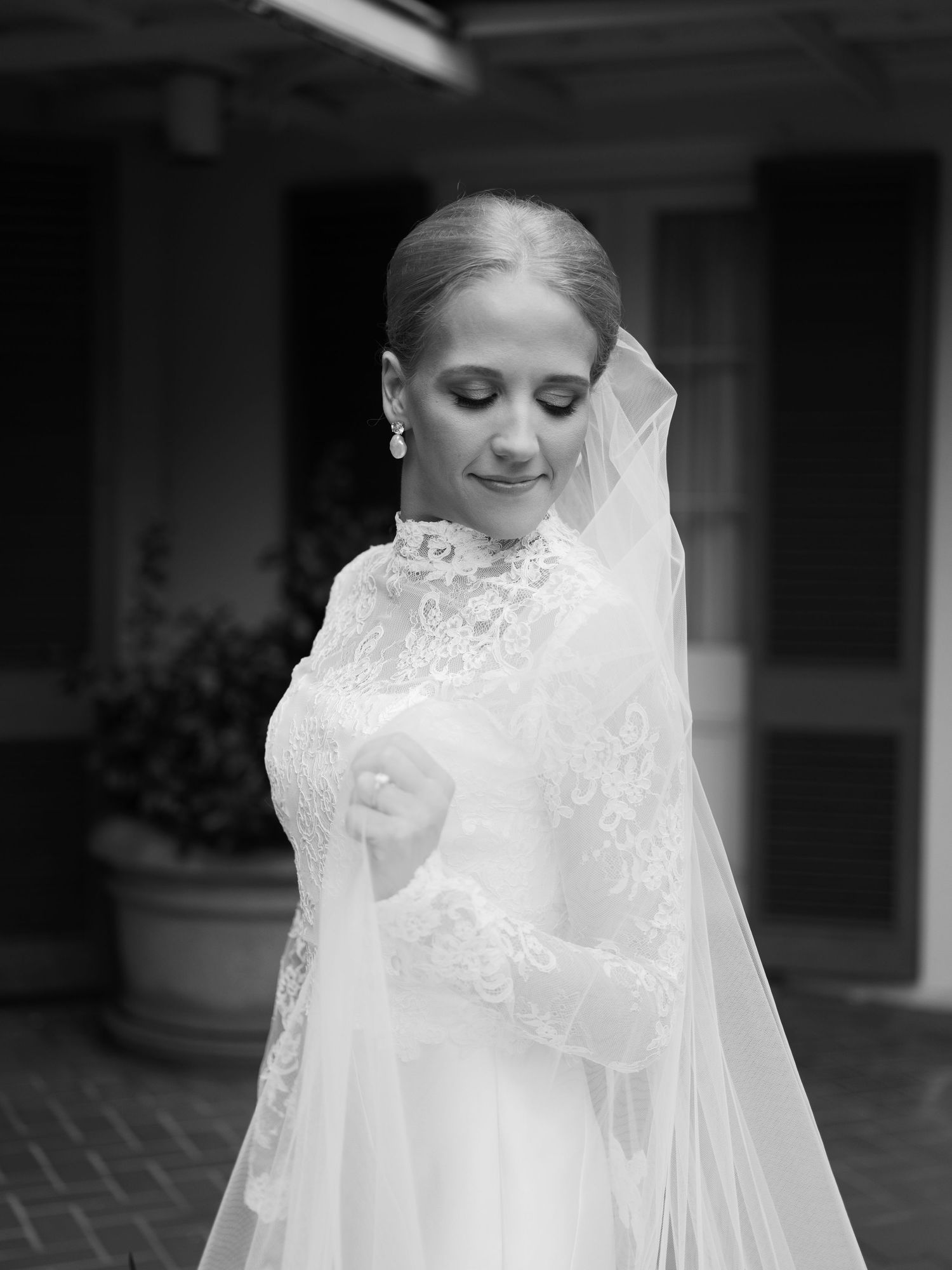 Black and white bridal portrait highlighting delicate lace details and flowing veil.