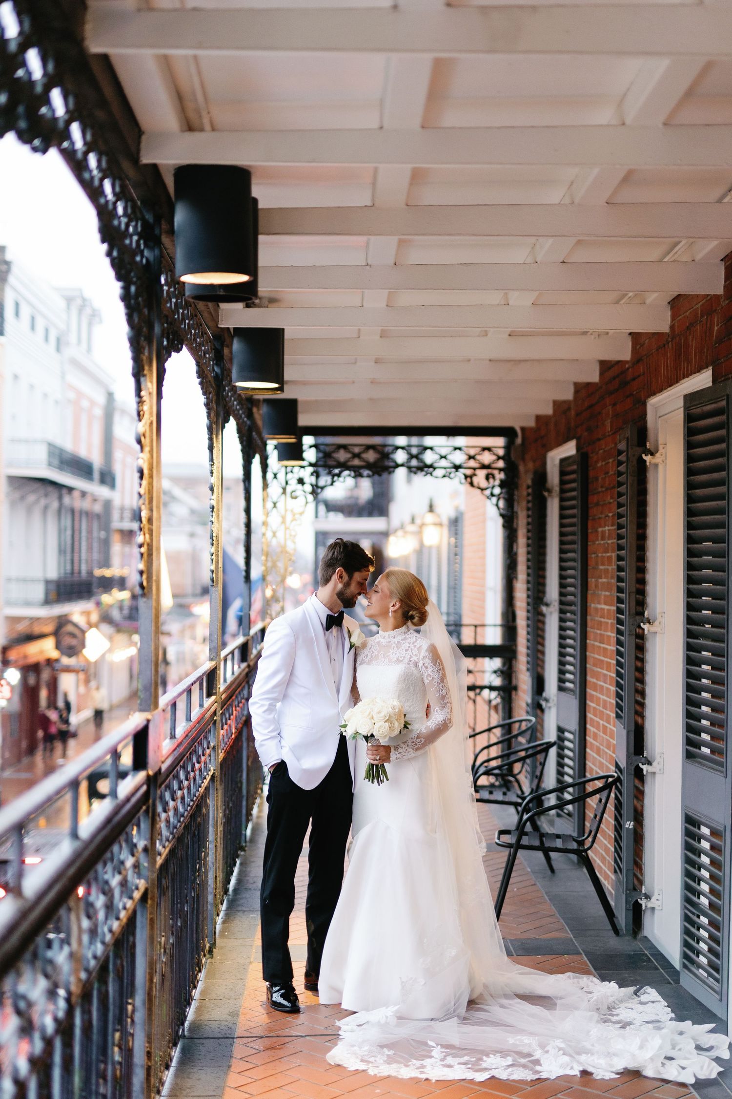 Romantic wedding portraits captured on a historic wrought-iron balcony with architectural details.