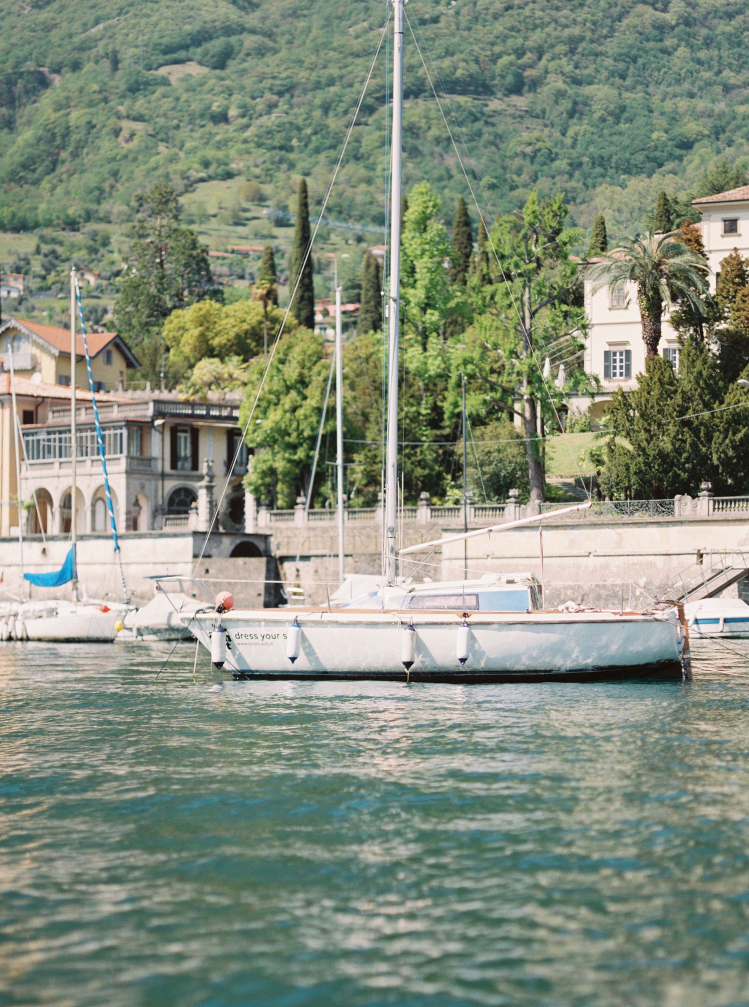 Waterfront villas and sailboats line the shore of a serene mountain lake.