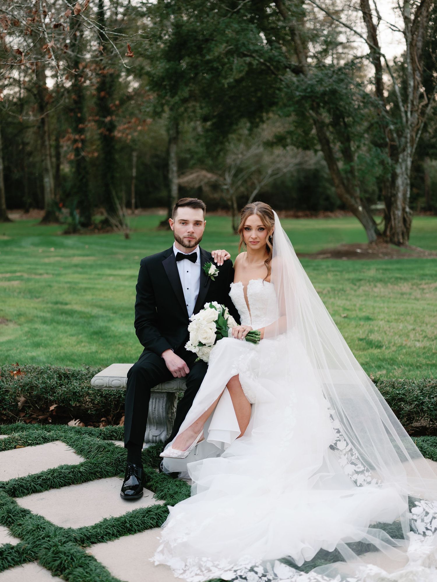 A romantic wedding photoshoot in a lush garden setting with a flowing white dress and classic tuxedo.