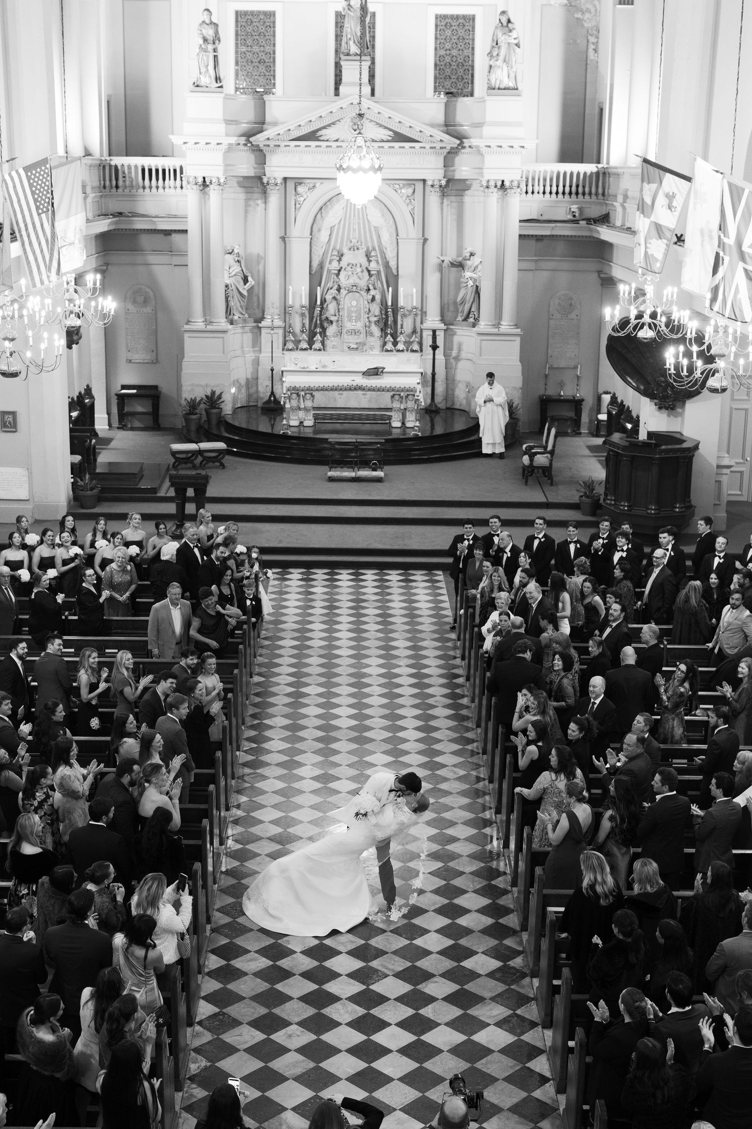 Aerial view of traditional church wedding ceremony with checkered floor and filled pews.