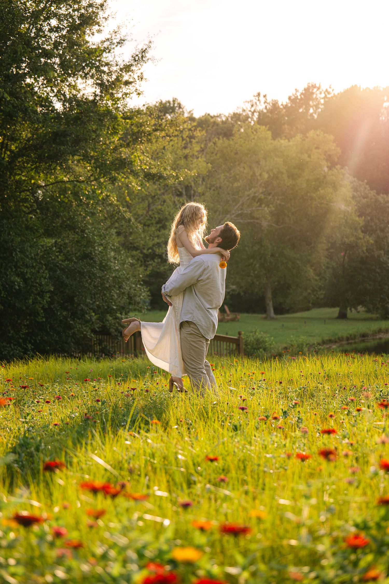 Harrison lifts Emily during their engagement session in a flower field in Gilbert, South Carolina.