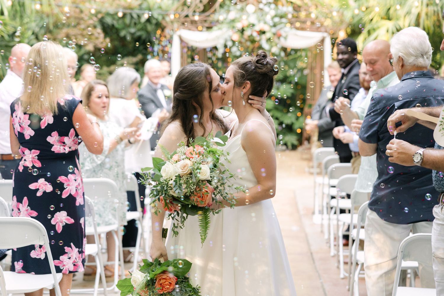 Brides kiss while walking down the aisle at River Road and Jasmine House Gardens in Columbia South Carolina