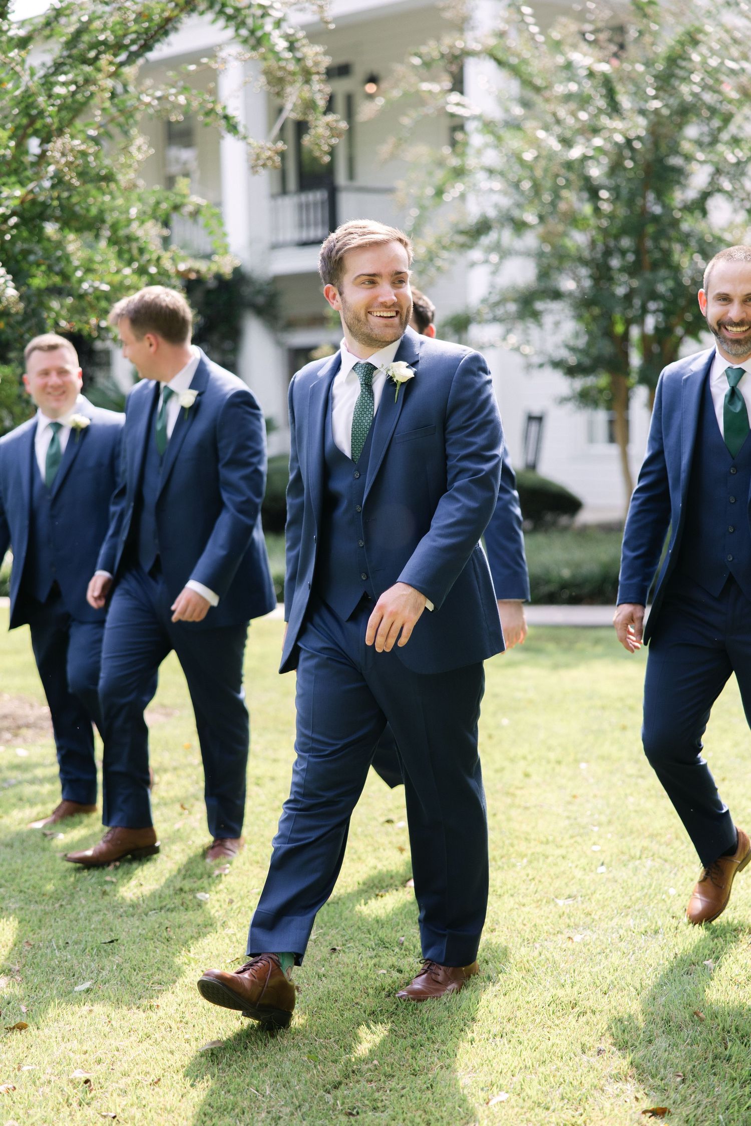 A groom and his groomsmen walk together in front of The Corley Mill House in Lexington, South Carolina.