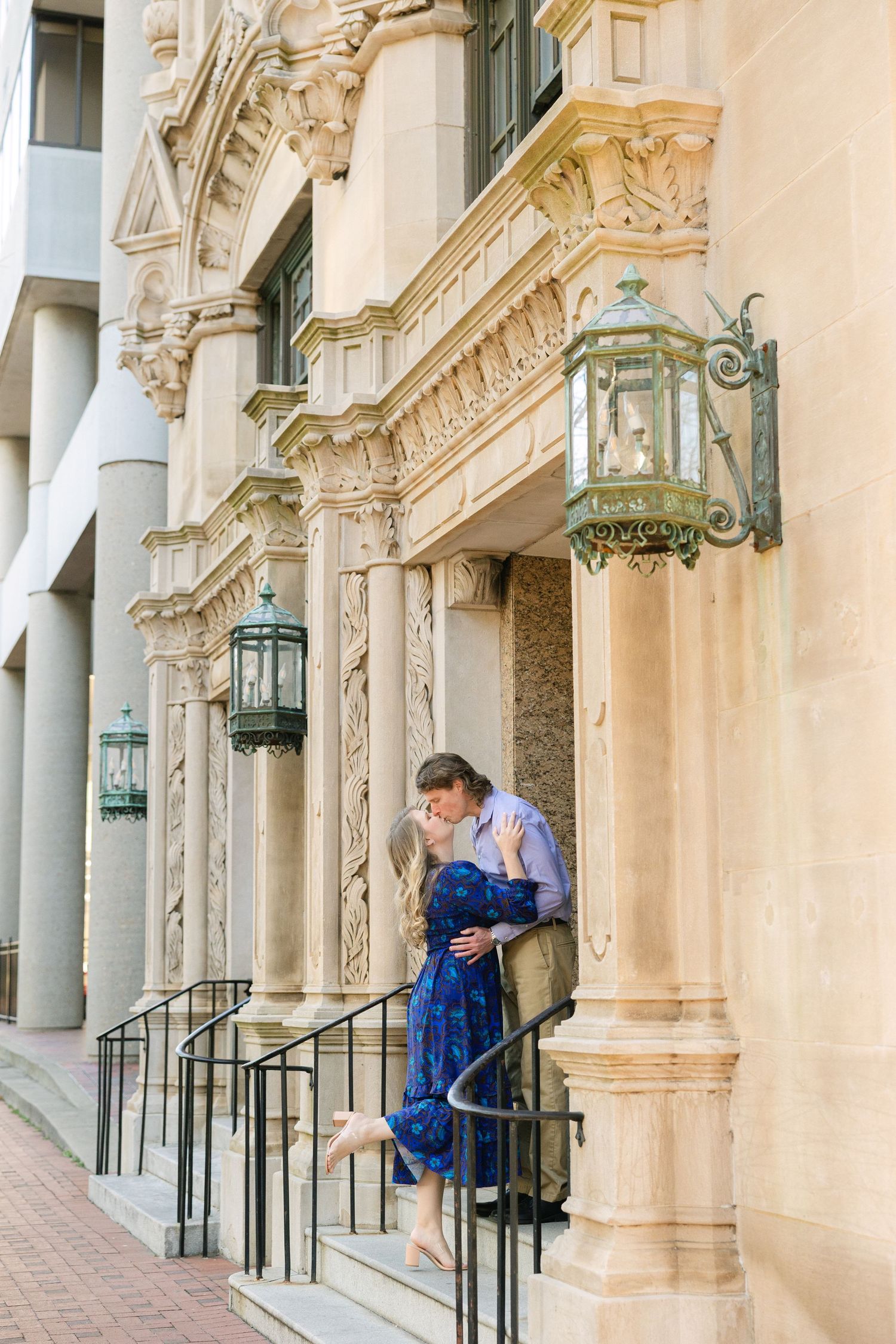A couple kisses on the steps of a building in downtown Columbia, South Carolina during their engagement session.