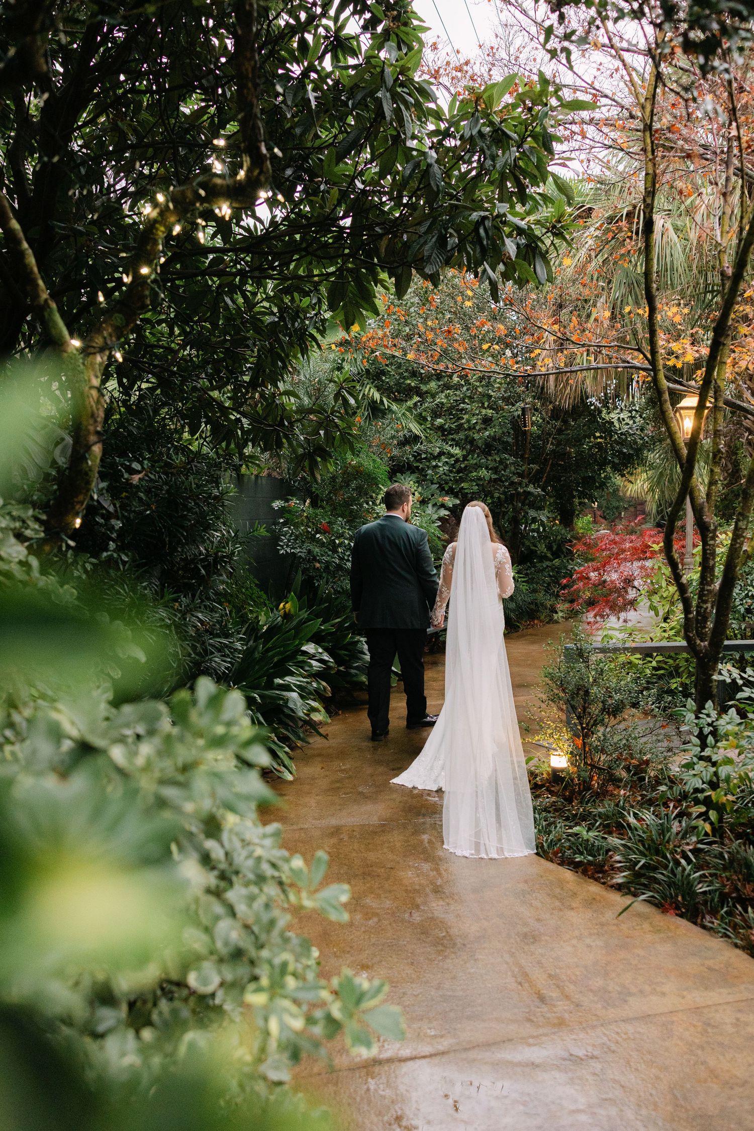 A bride and groom walk through the gardens on their wedding day at The River Road and Jasmine House in Columbia, SC.