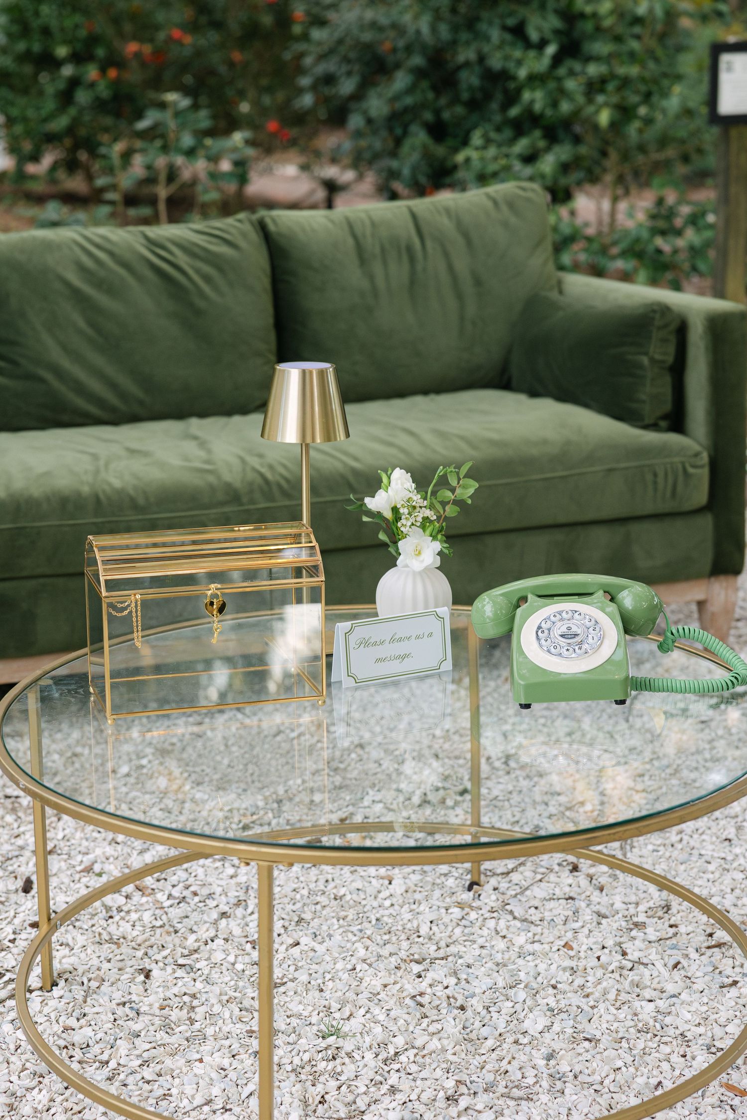 Elegant outdoor wedding lounge setup with green velvet couch and candlelit glass coffee table