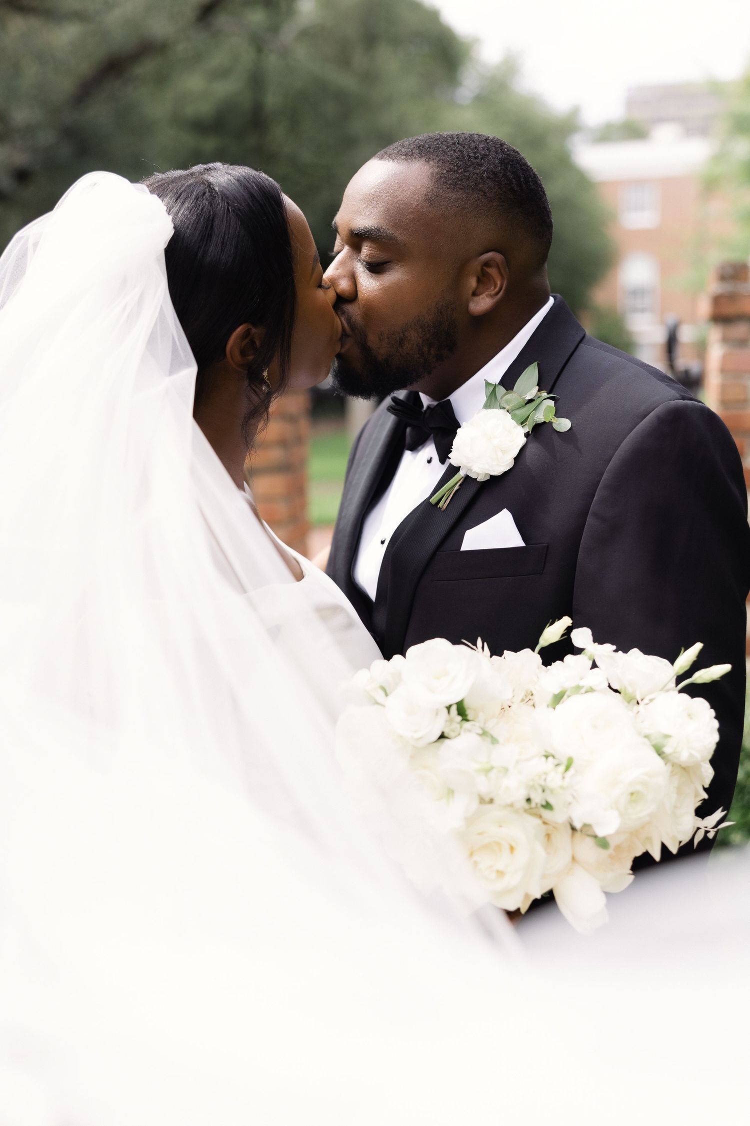 A couple kisses for a traditional veil portrait on their wedding day in SC.