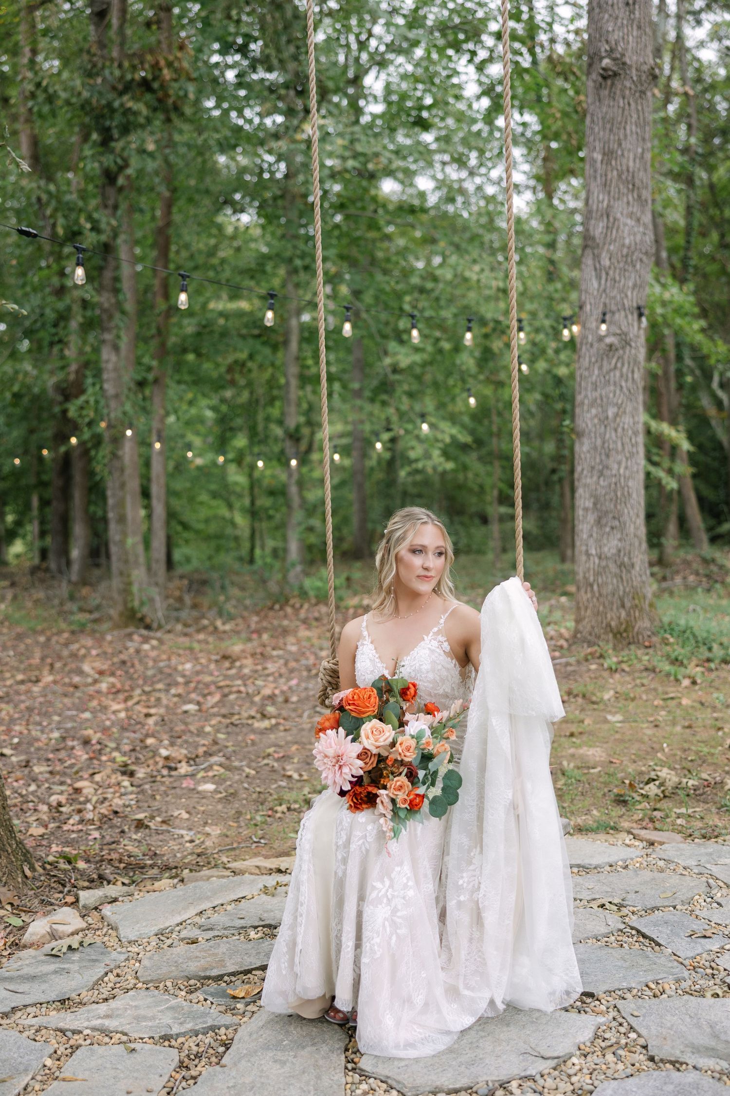 A bride poses for a moody portrait on a swing at Piney Grove Ranch in South Carolina.