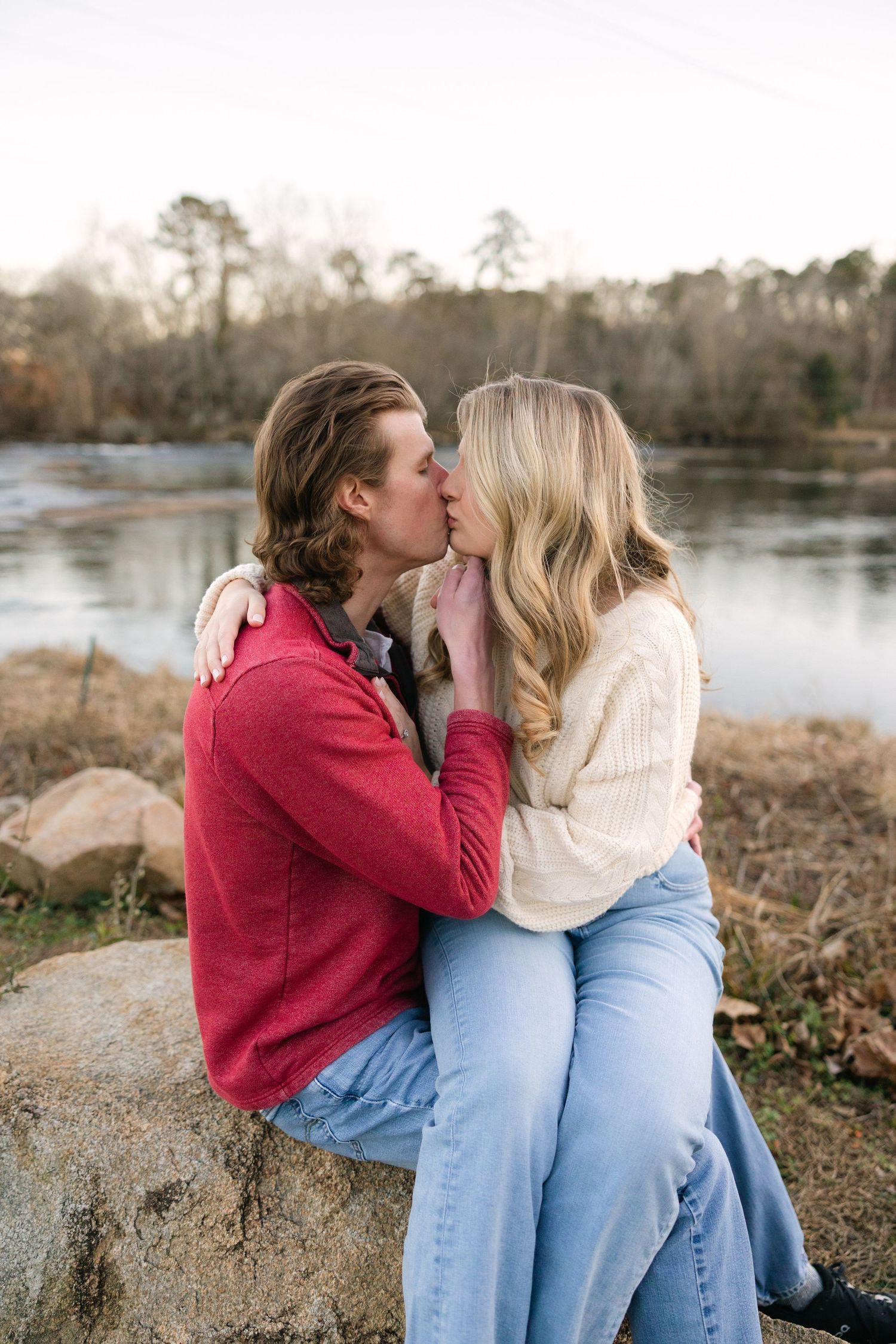 A couple kisses on the rocks at the Saluda Riverwalk during their engagement session in Columbia, SC.