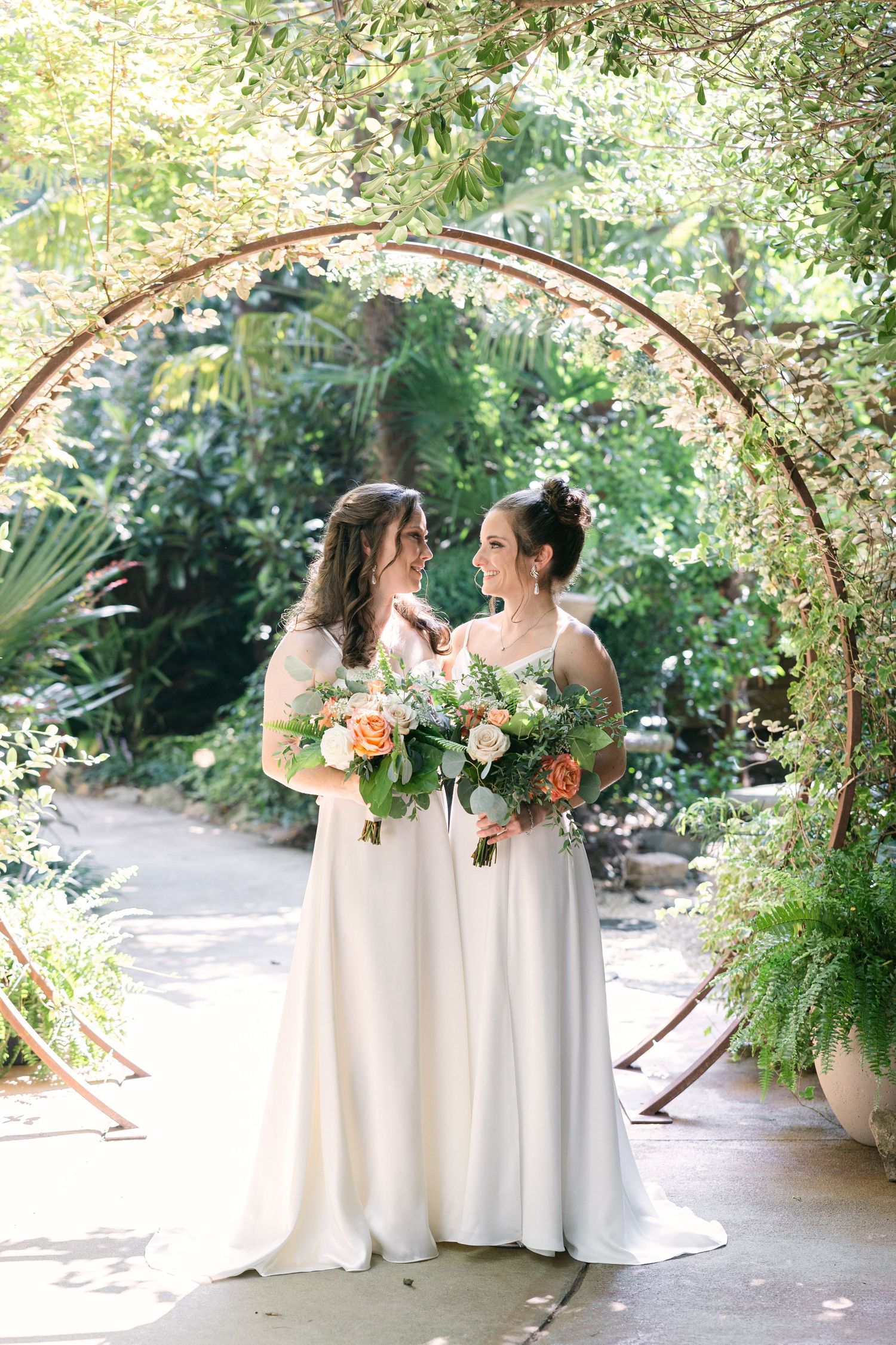 Two brides smile at each other on their wedding day at the River Road and Jasmine House in Columbia, SC.