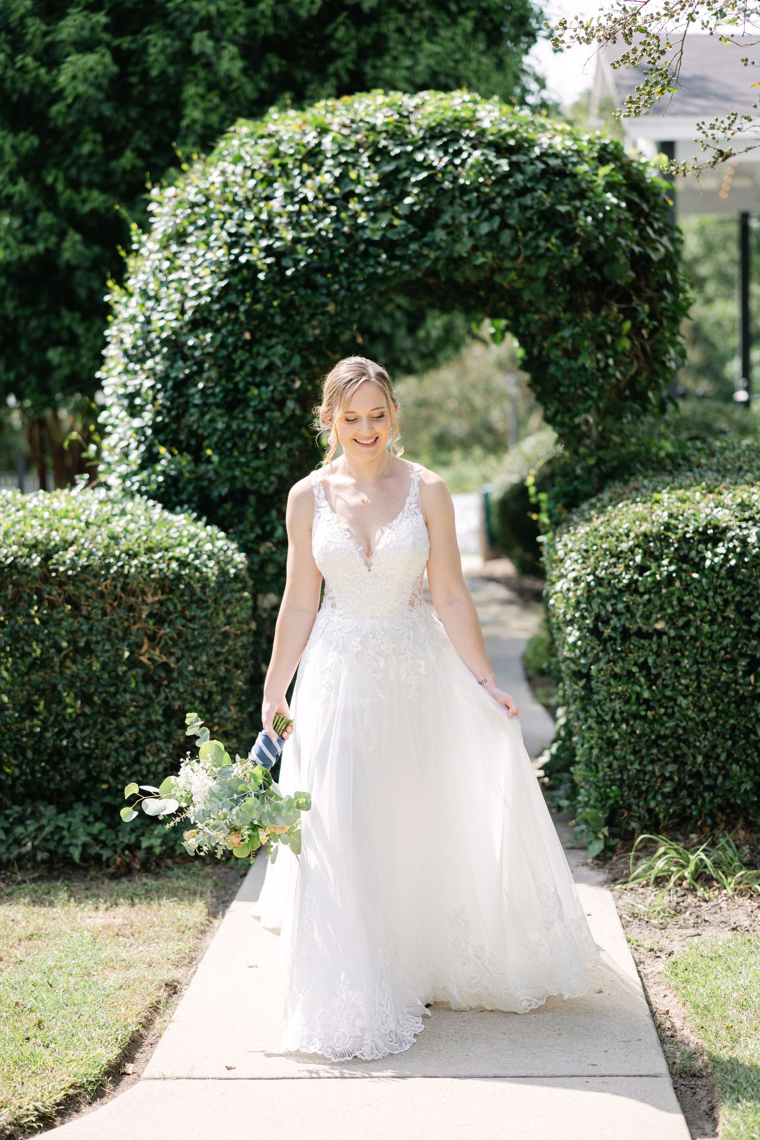 Bride standing beneath greenery arch at Corley Mill House wedding in Columbia South Carolina