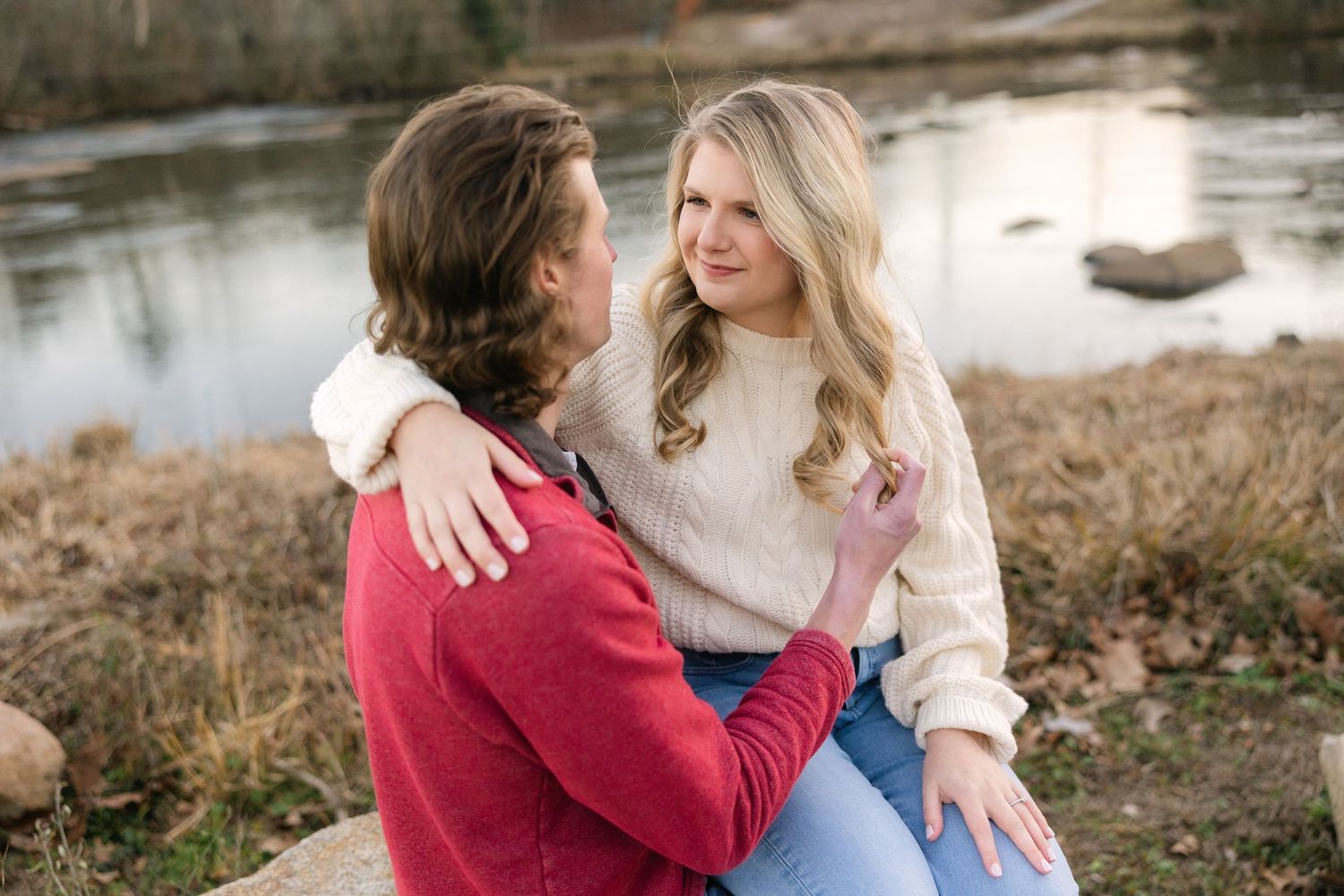 A couple sits on the rocks and looks at each other at the Saluda Riverwalk in Columbia, SC.