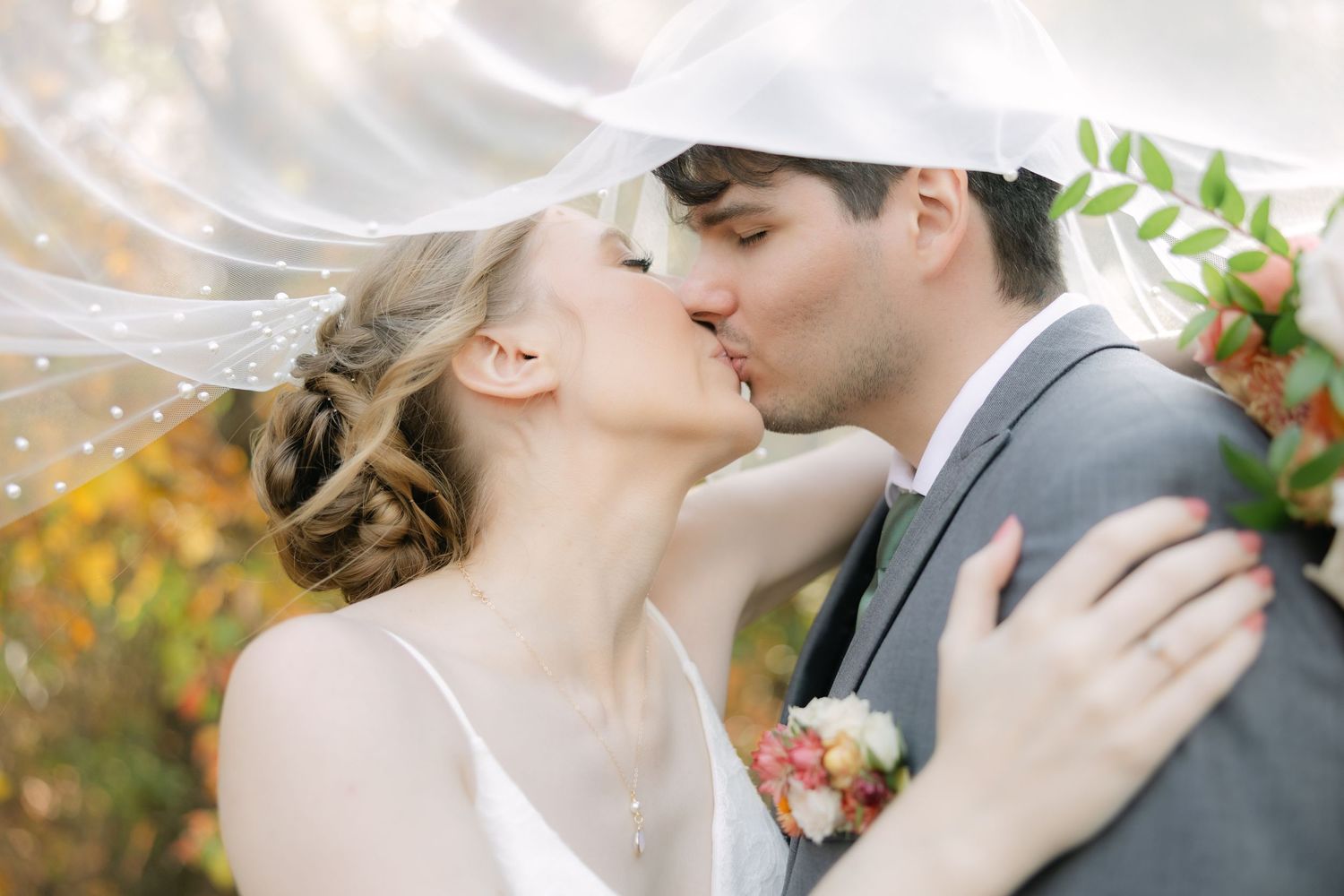 Groom kissing bride’s temple under flowing veil during romantic garden wedding in South Carolina