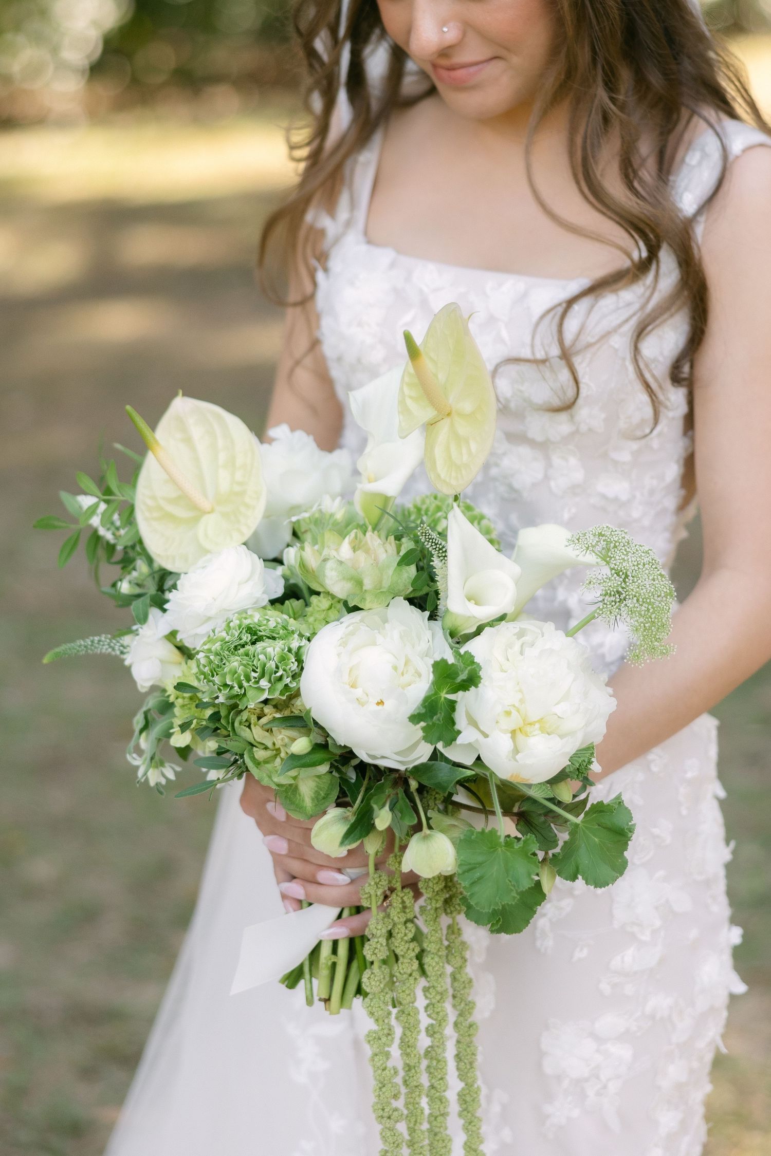 Bride in lace wedding dress holding white and green bouquet during outdoor ceremony in South Carolina