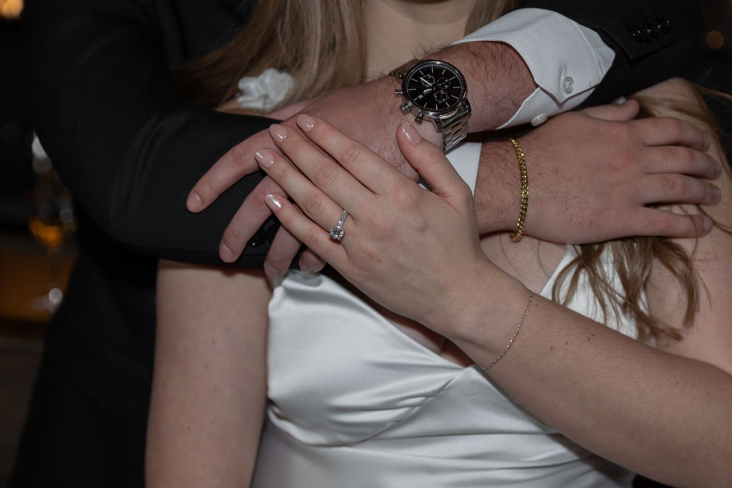 Close-up of bride and groom hands showing engagement ring, wedding bracelet, and watch during wedding dance.