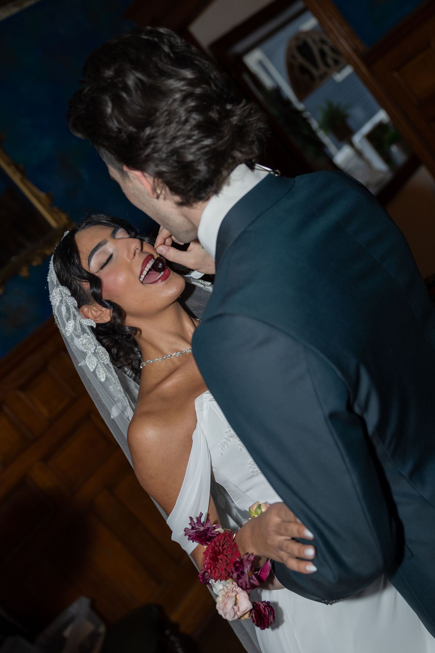 Bride and groom sharing a joyful moment during their wedding reception, with the bride laughing in a white gown and veil.