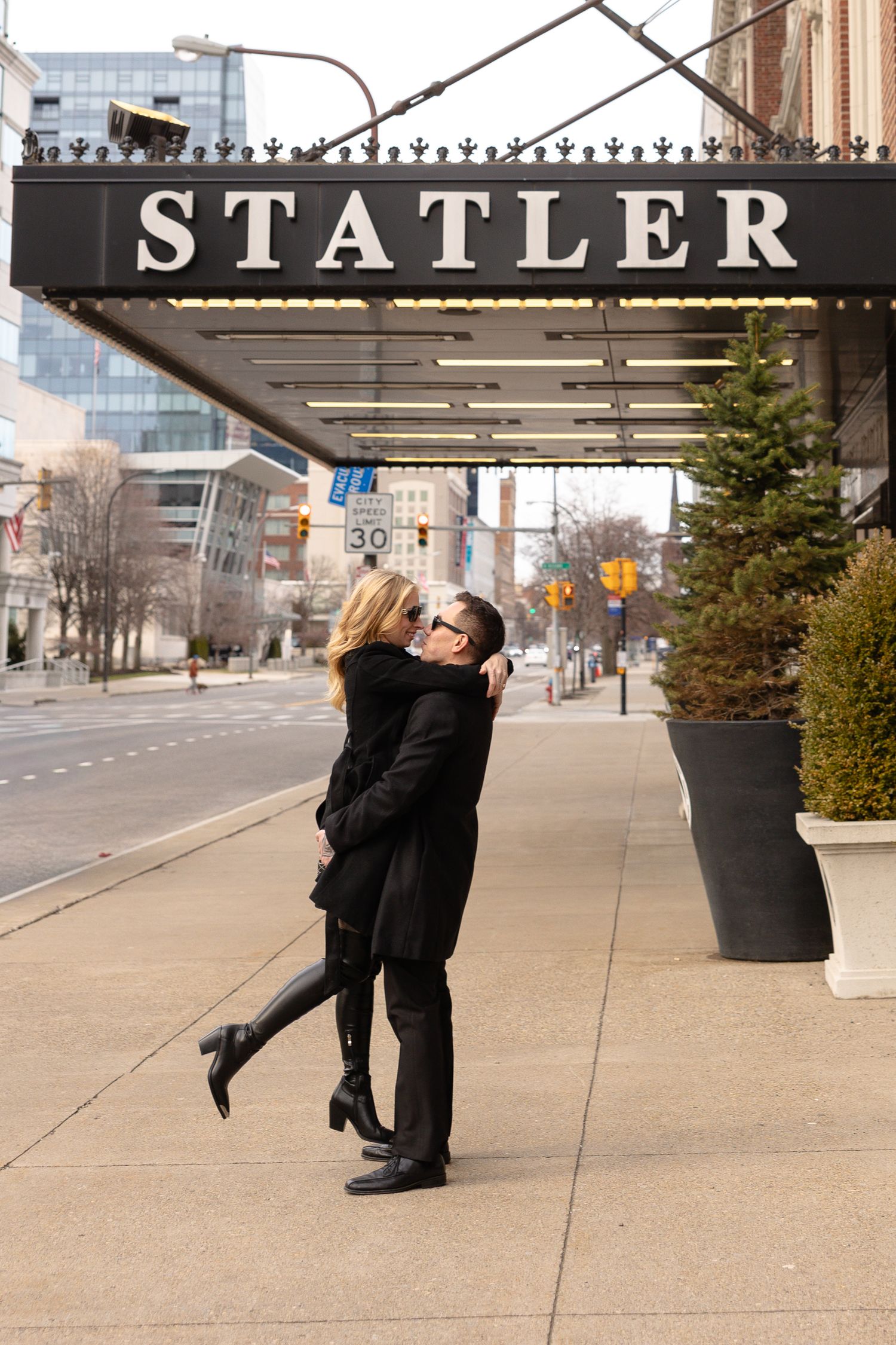Couple kissing and embracing in front of the Statler Hotel marquee sign on a city sidewalk in Buffalo New York