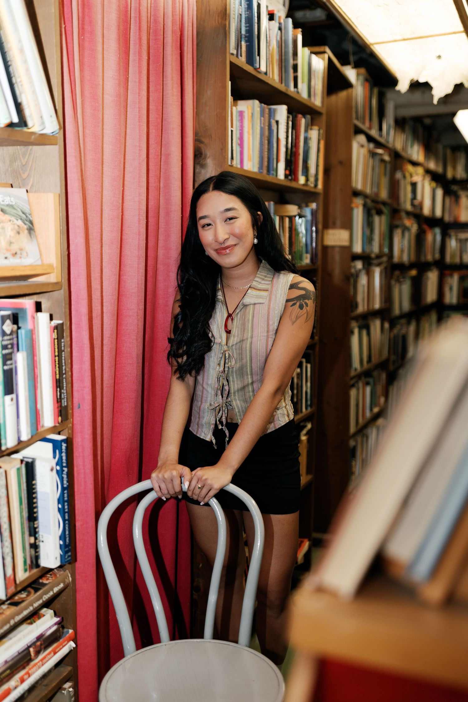 Portrait session in library featuring red curtains and wooden bookshelves.