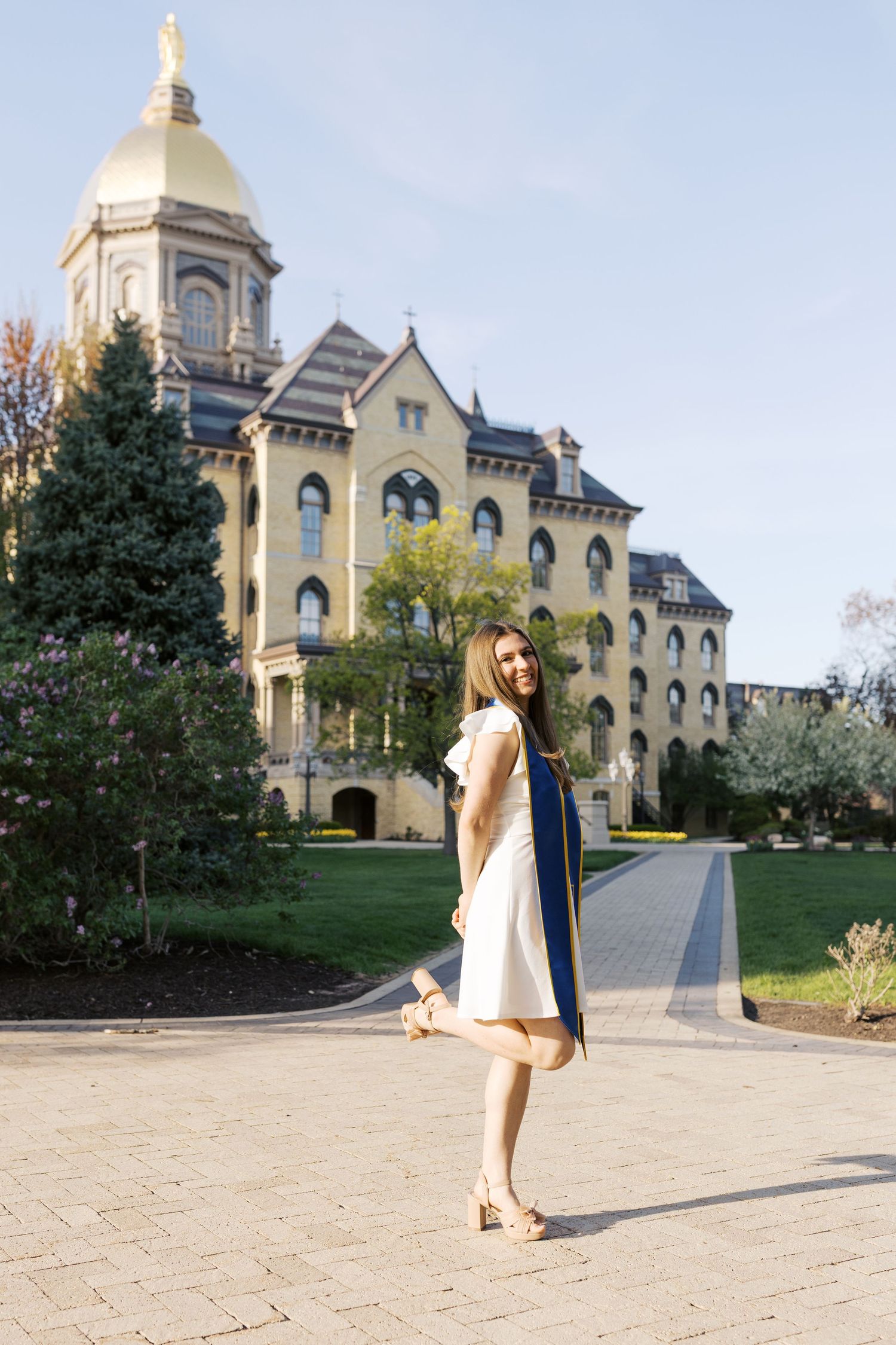 Graduate walks up stone path leading to majestic Gothic university building.