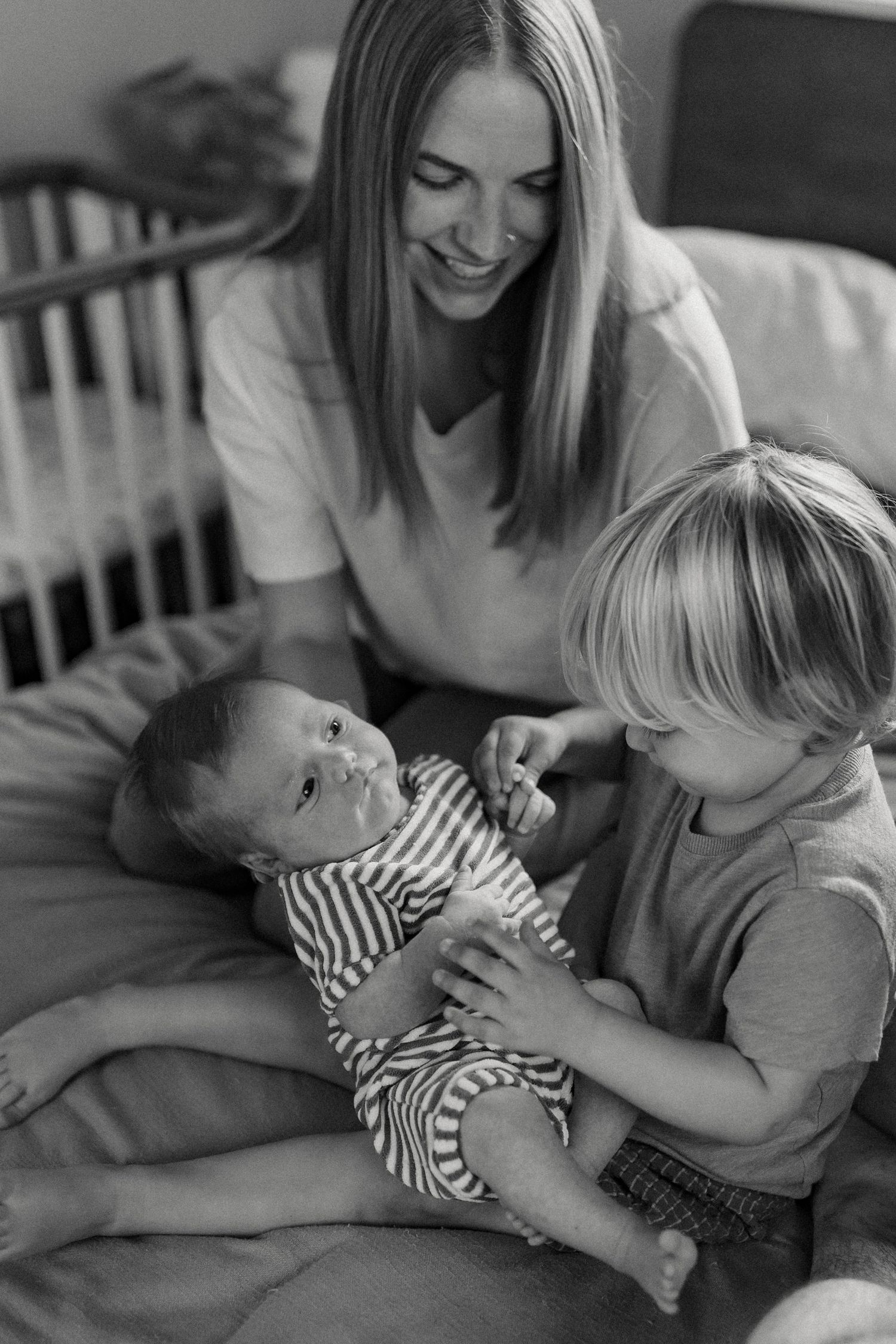 Black and white candid family moments captured on bed.