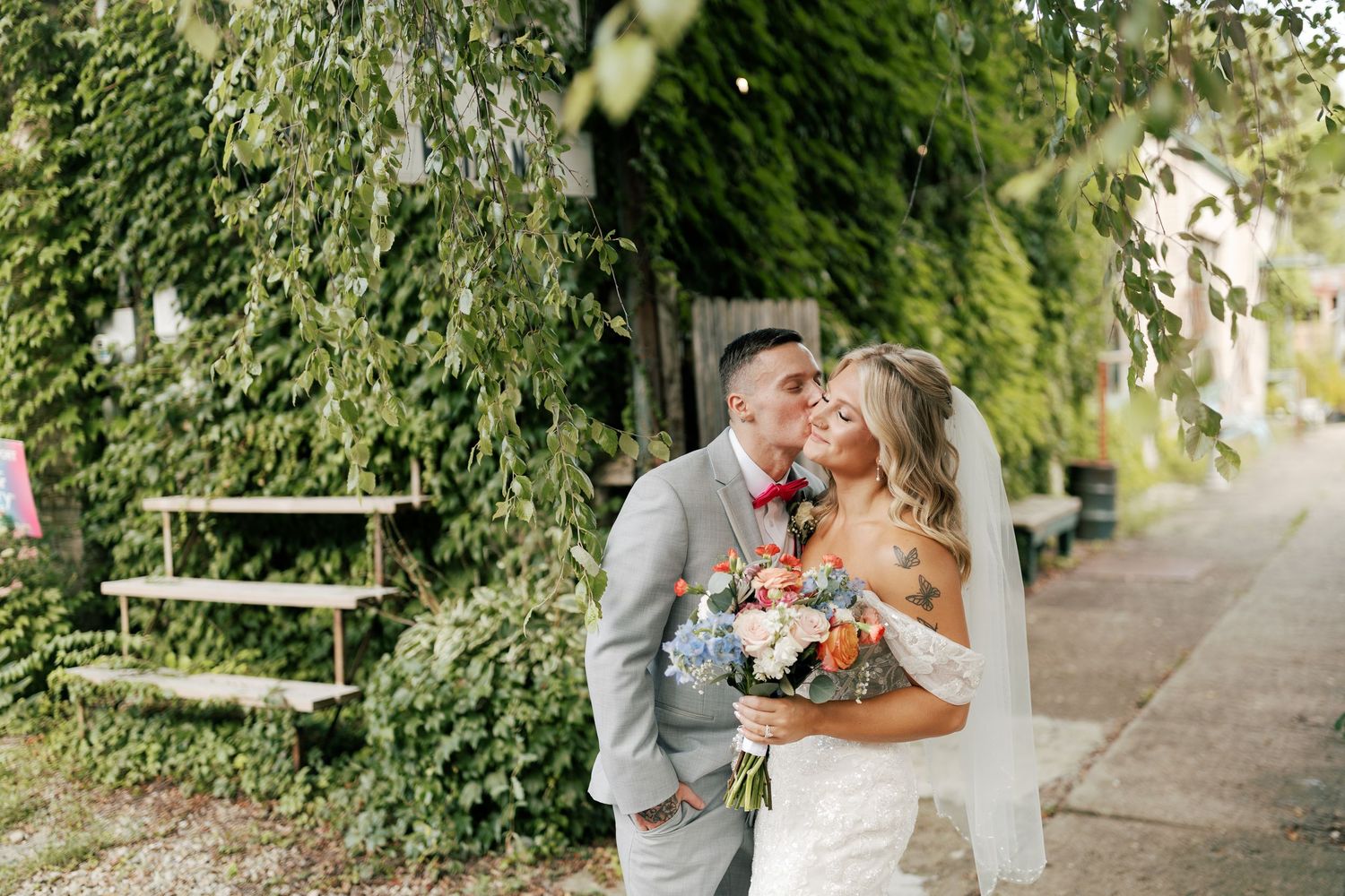 Wedding couple walking and laughing together along ivy-covered garden path.