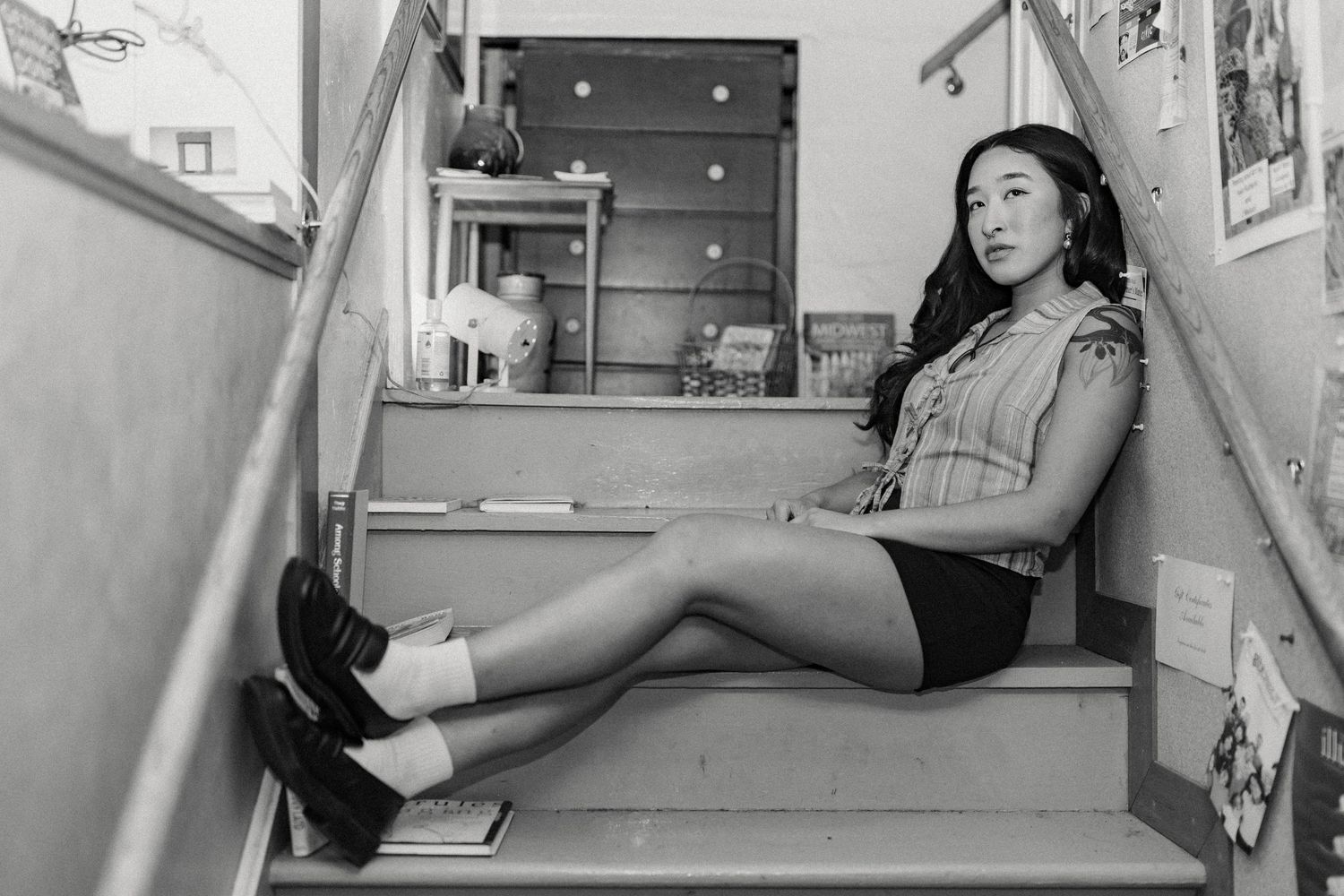 Black and white photo of person lounging casually in a library setting.