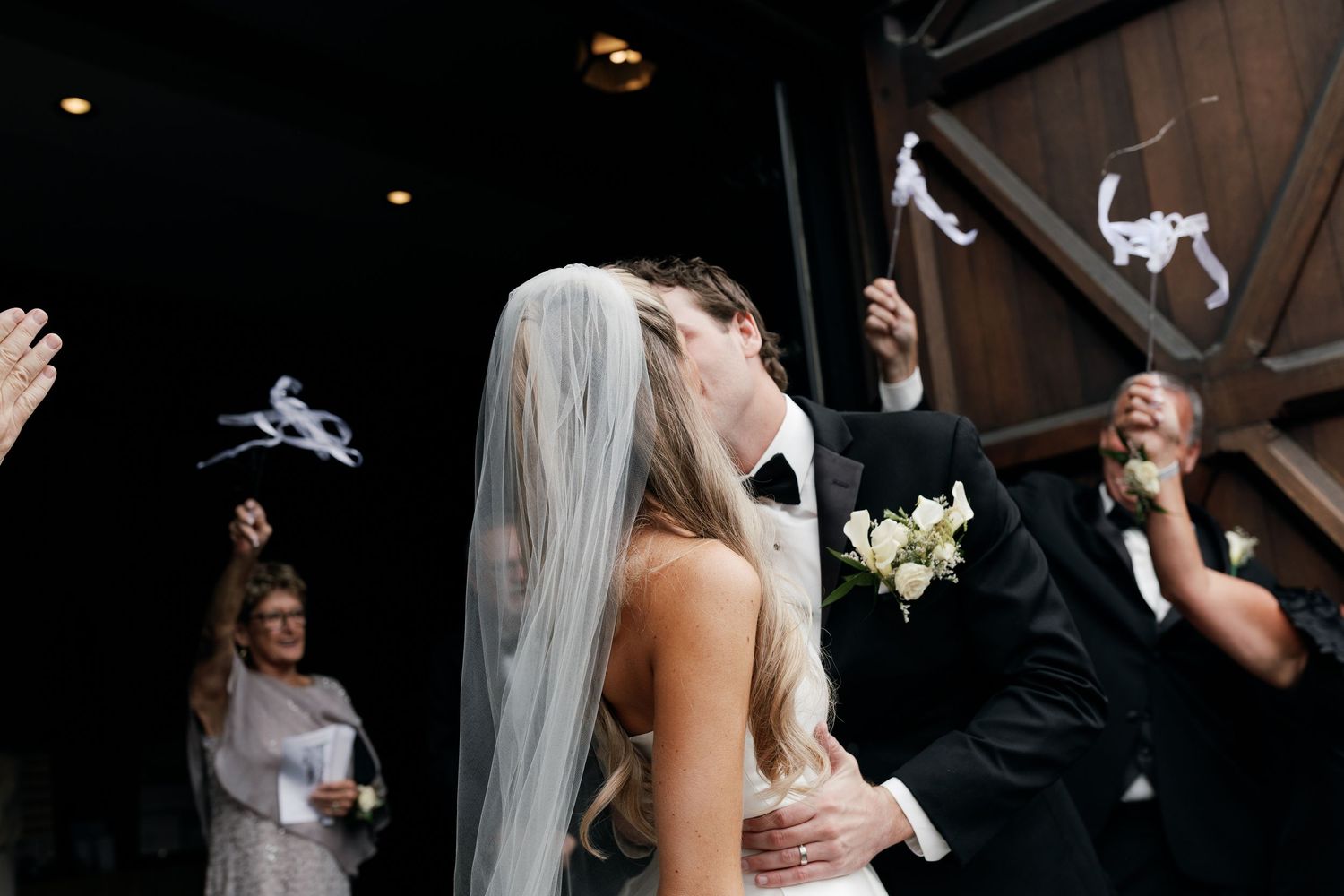 Wedding guests dance and celebrate joyfully at an indoor reception.