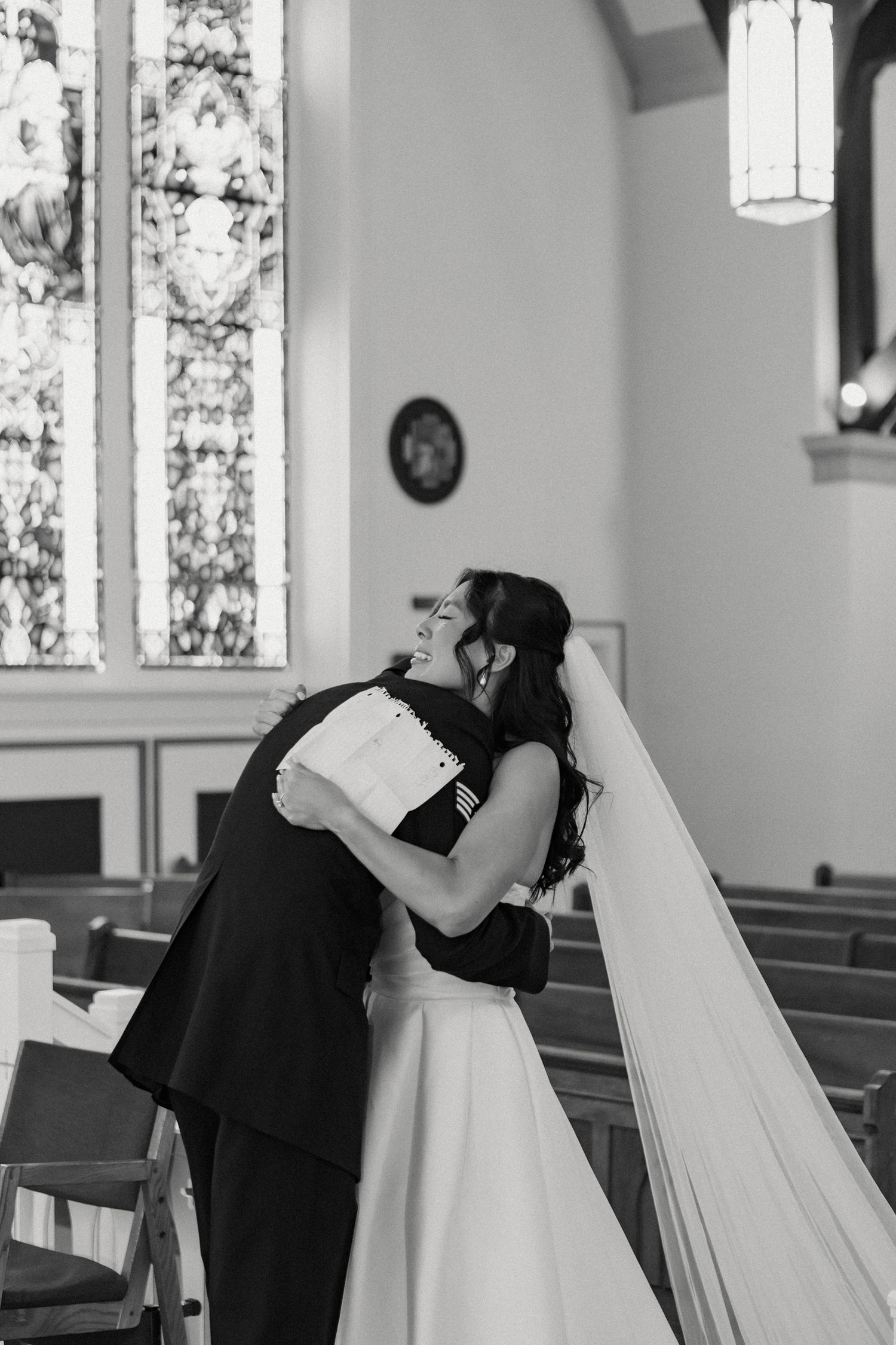 Black and white photos of a romantic moment in a church with stained glass windows.