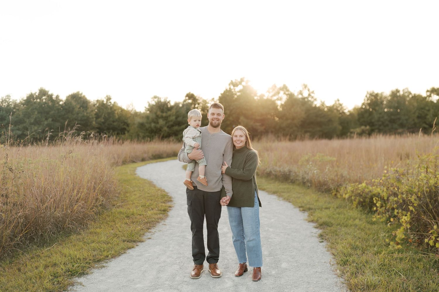 A family walking together on a winding path during golden hour in a natural field setting.