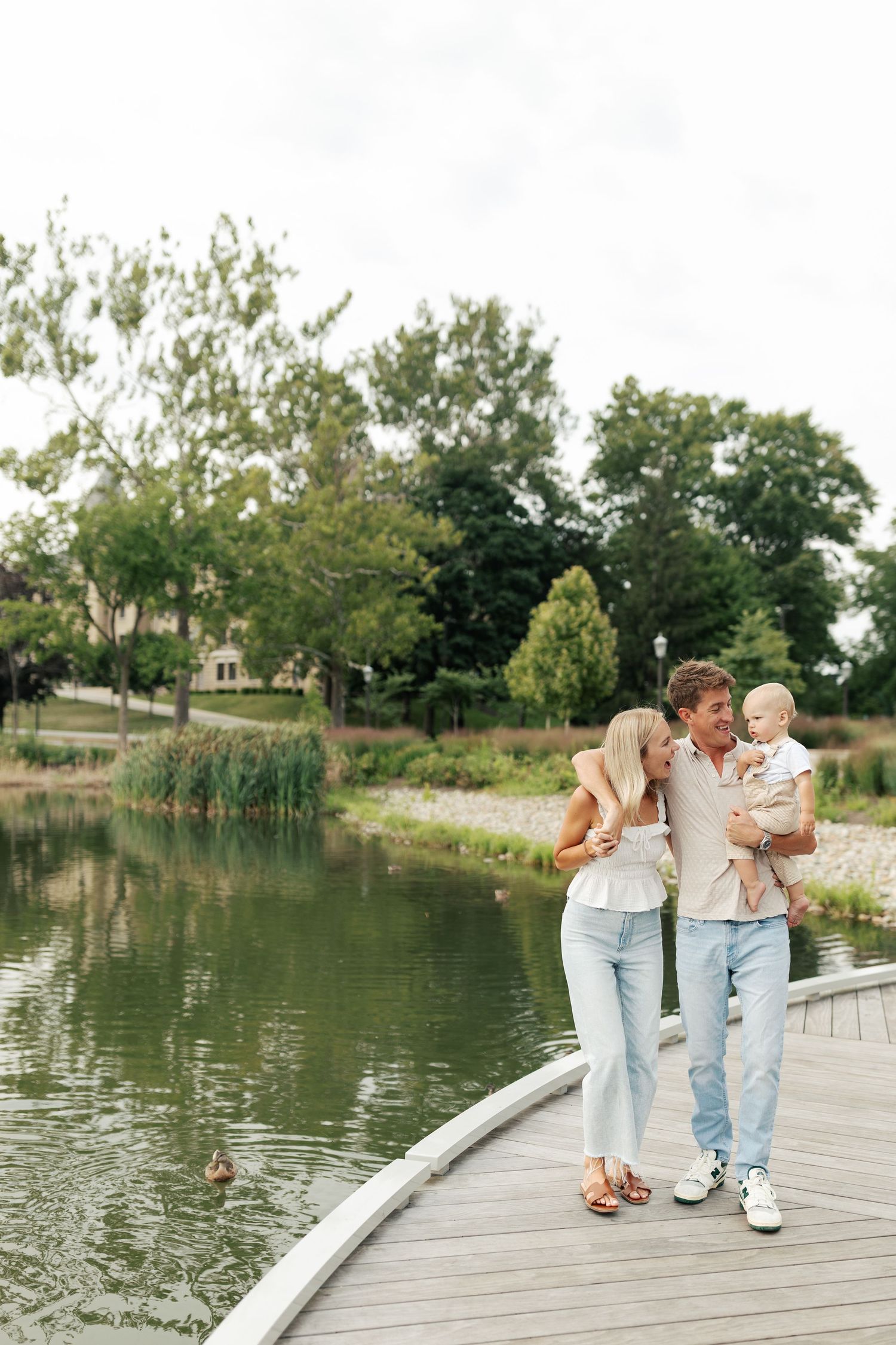 Family taking a leisurely stroll along a curved wooden boardwalk by the water.