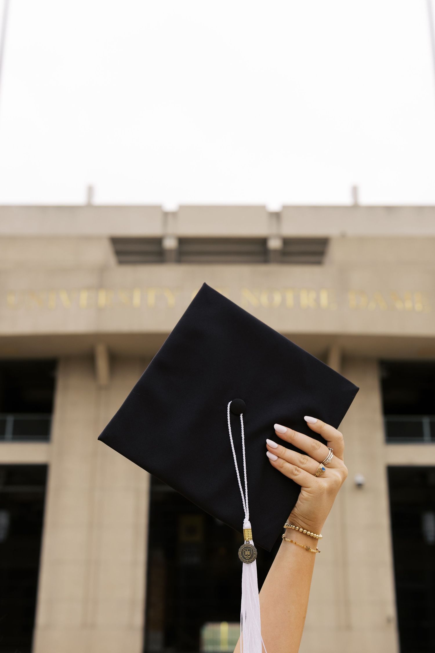 Graduation cap held up against a blurred building background with white columns.