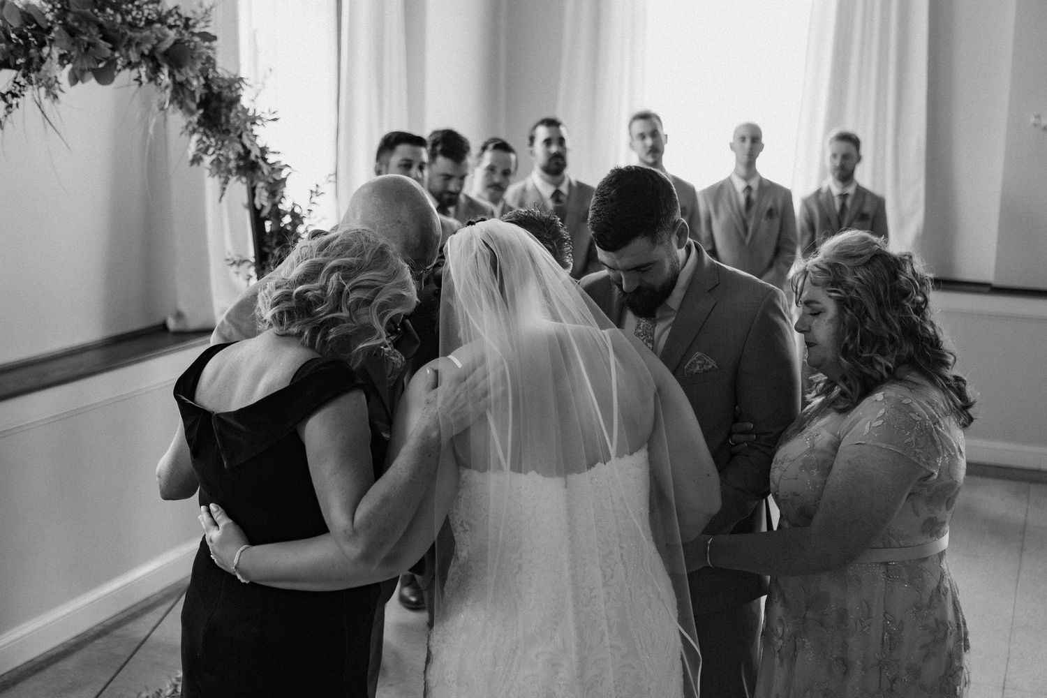 Black and white photo of a wedding ceremony with guests standing in rows watching the proceedings.