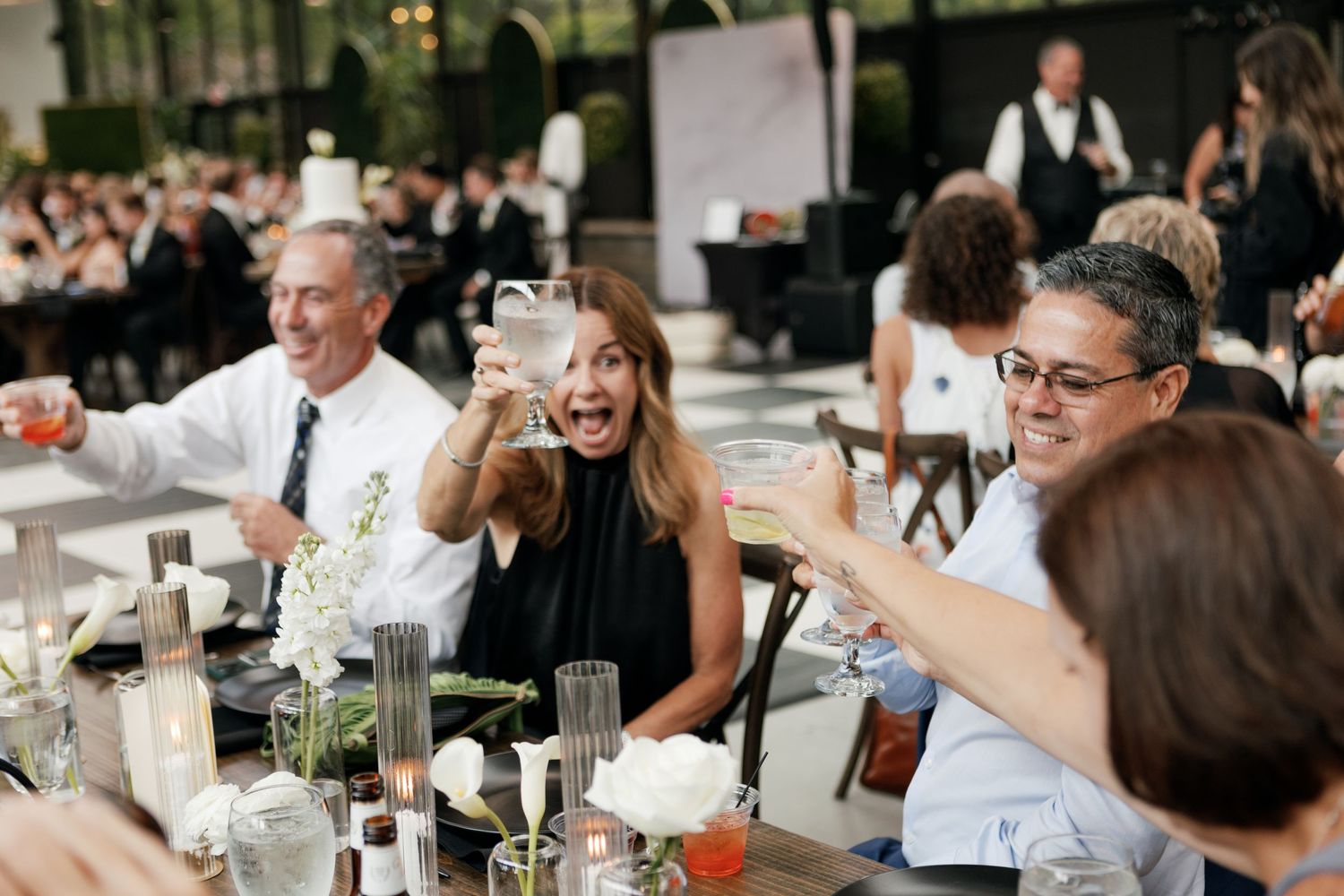 Wedding guests mingle and celebrate at reception tables.